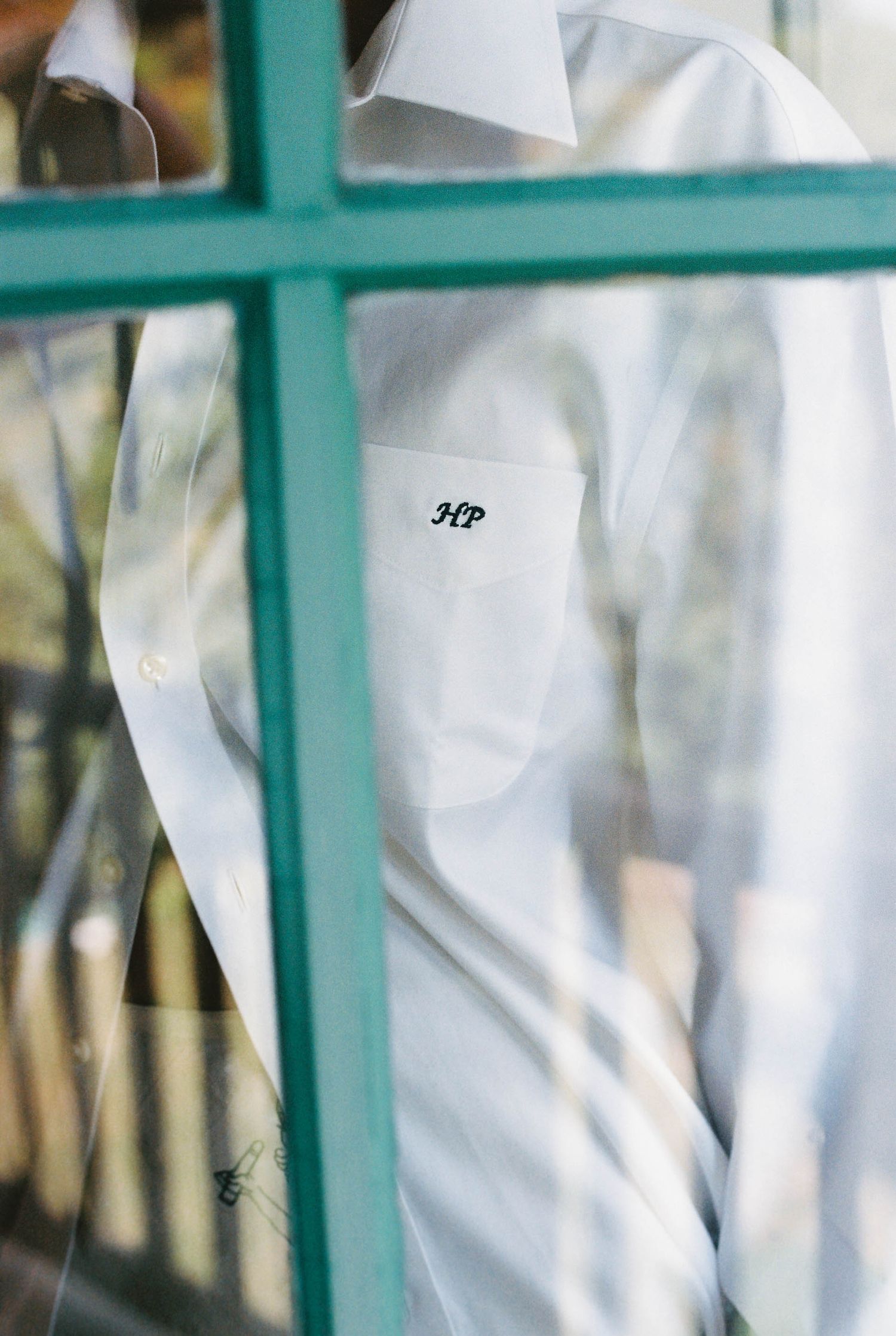 A close-up view through turquoise window panes of white wedding attire.