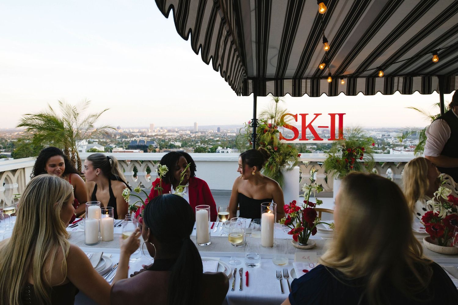 Outdoor dining setup with SK-II branding and string lights under a striped awning.