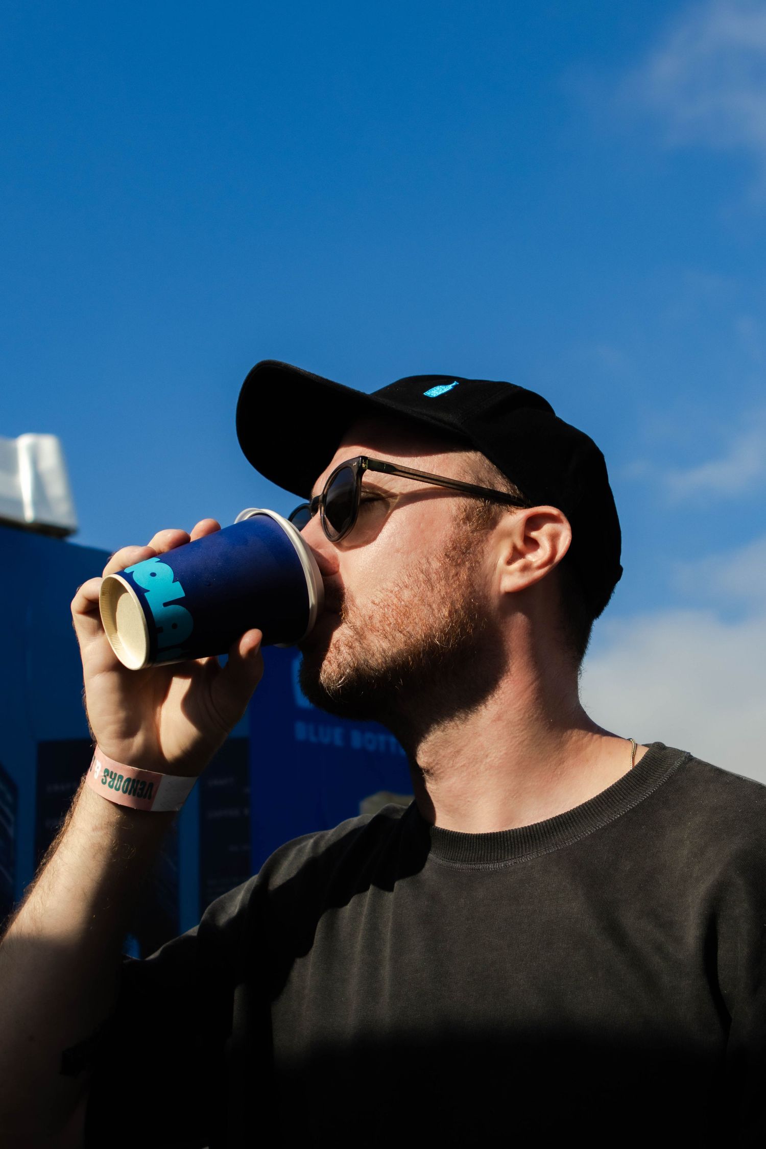 Silhouetted profile drinking from a branded coffee cup against a blue sky.