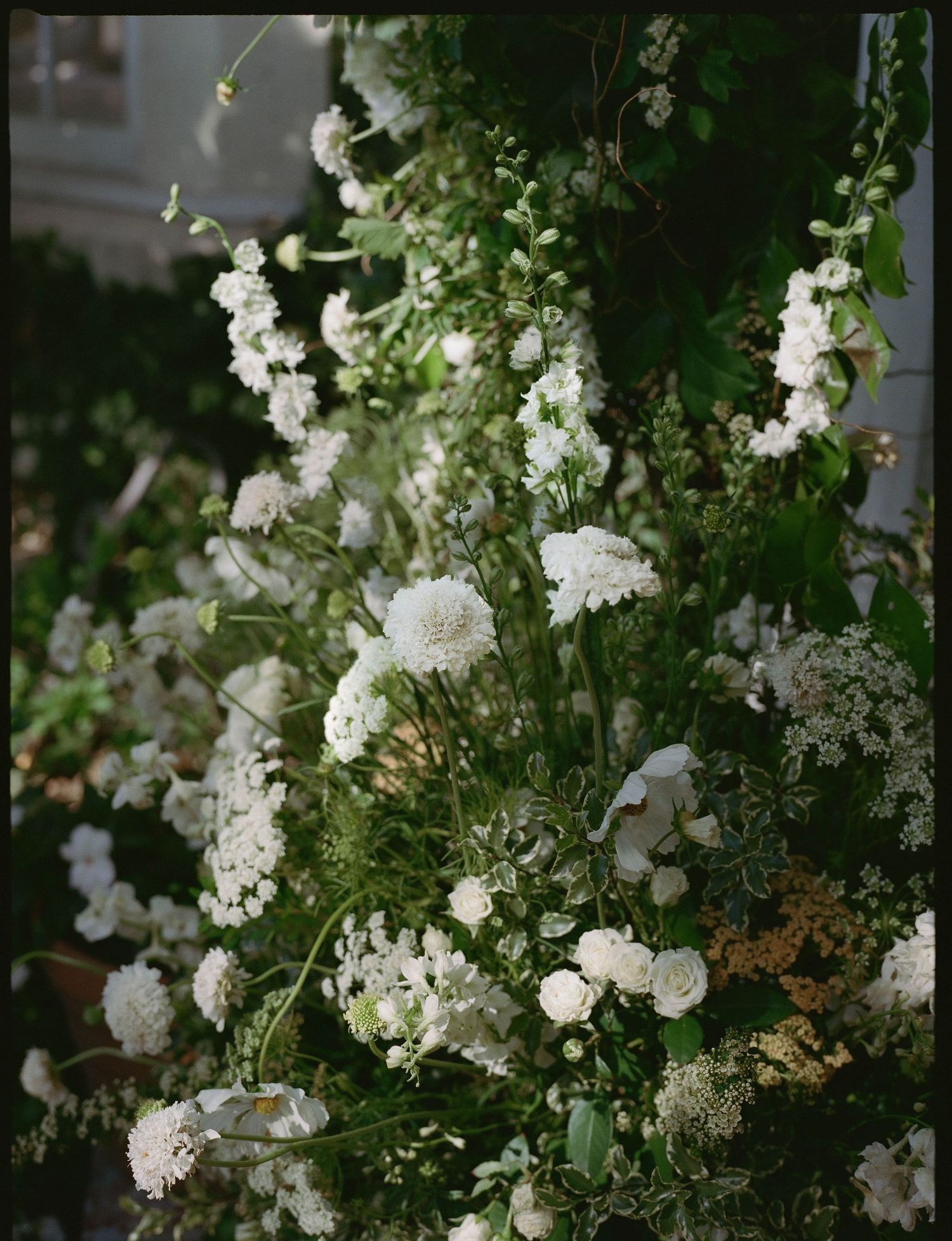 Lush arrangement of white flowers and green foliage creating an elegant floral display for a wedding ceremony.