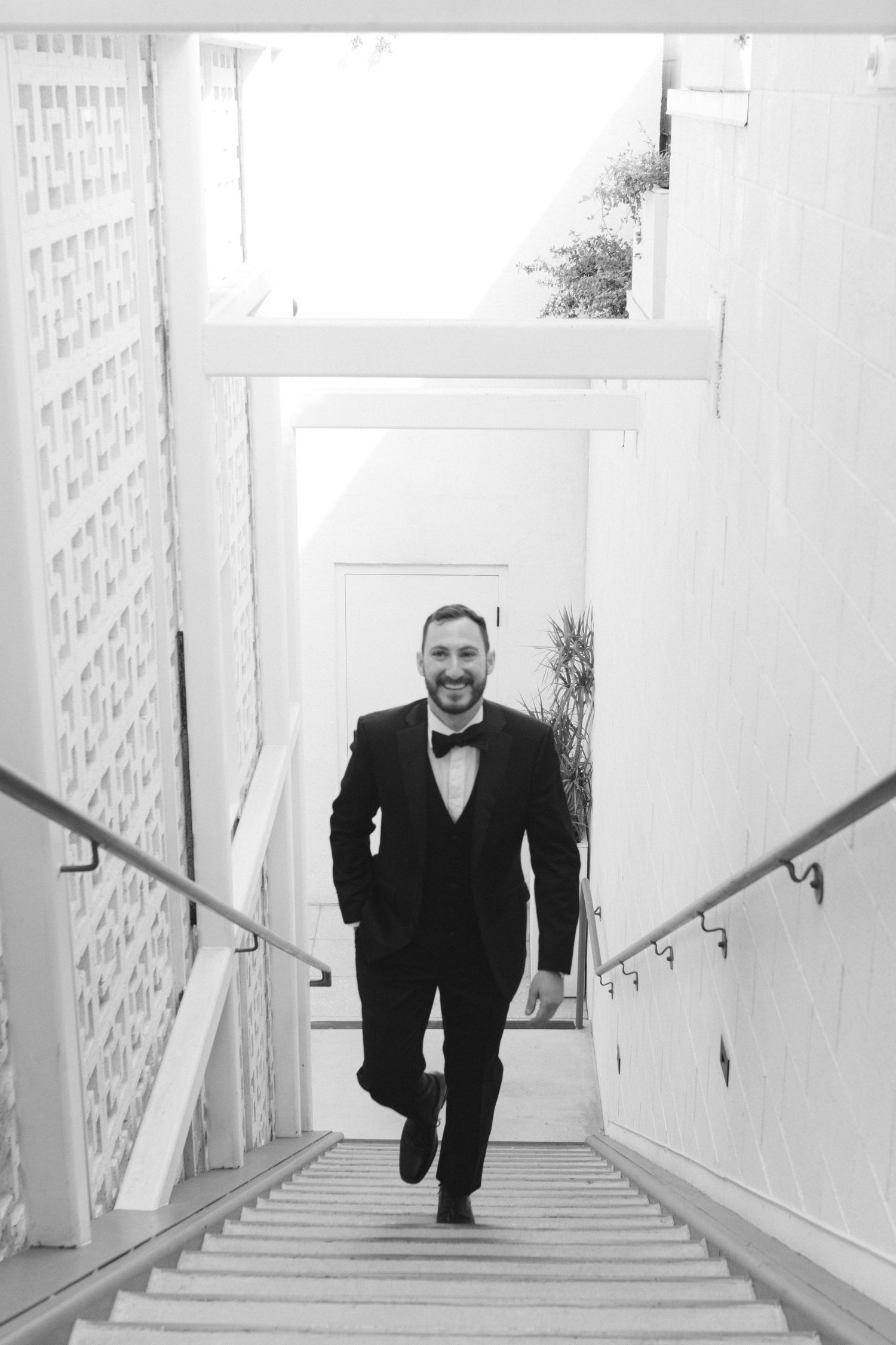 Black and white photos of men walking up white stairs with geometric wall patterns.