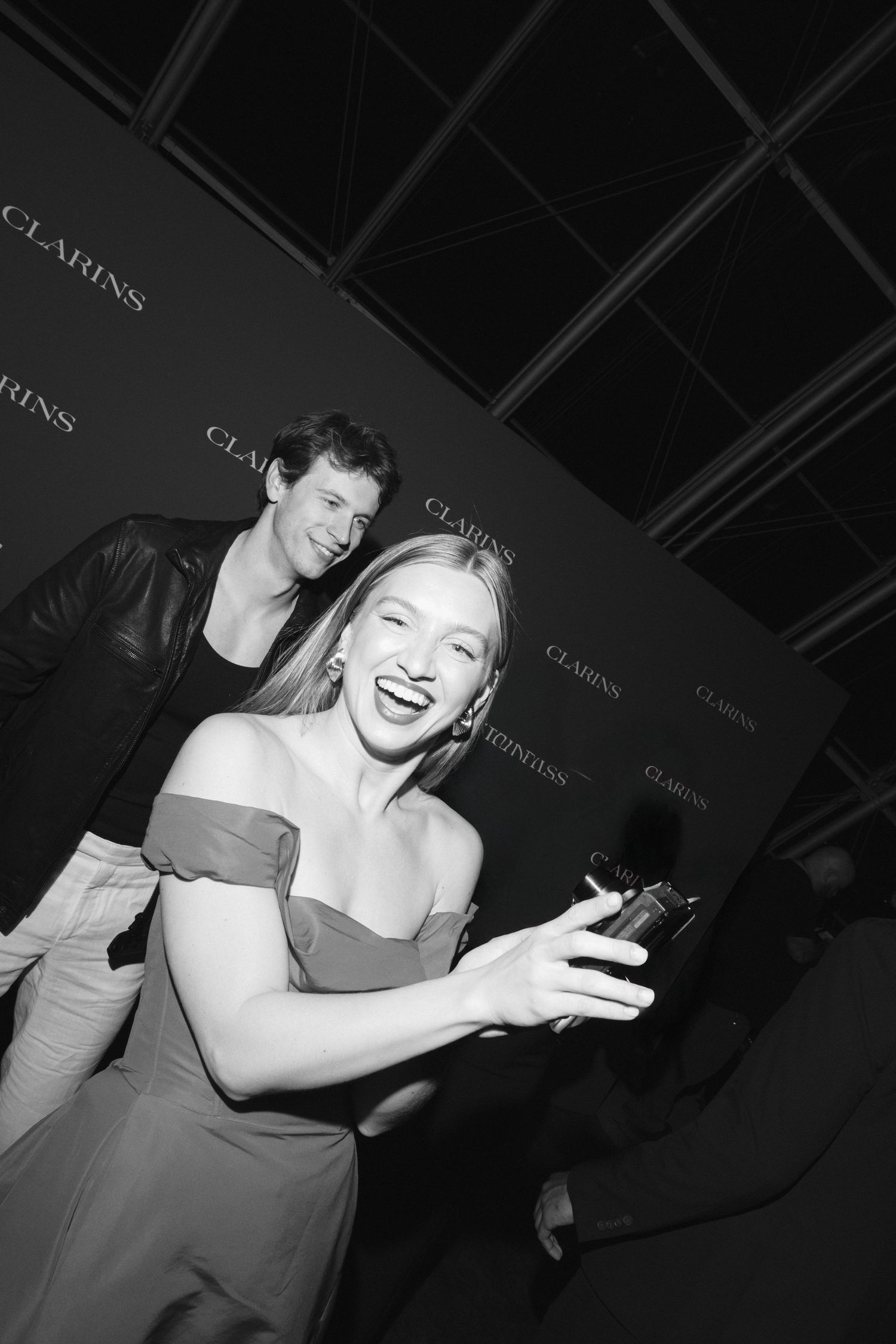 A sequence of black and white photos showing someone laughing and making expressive gestures at a social event.