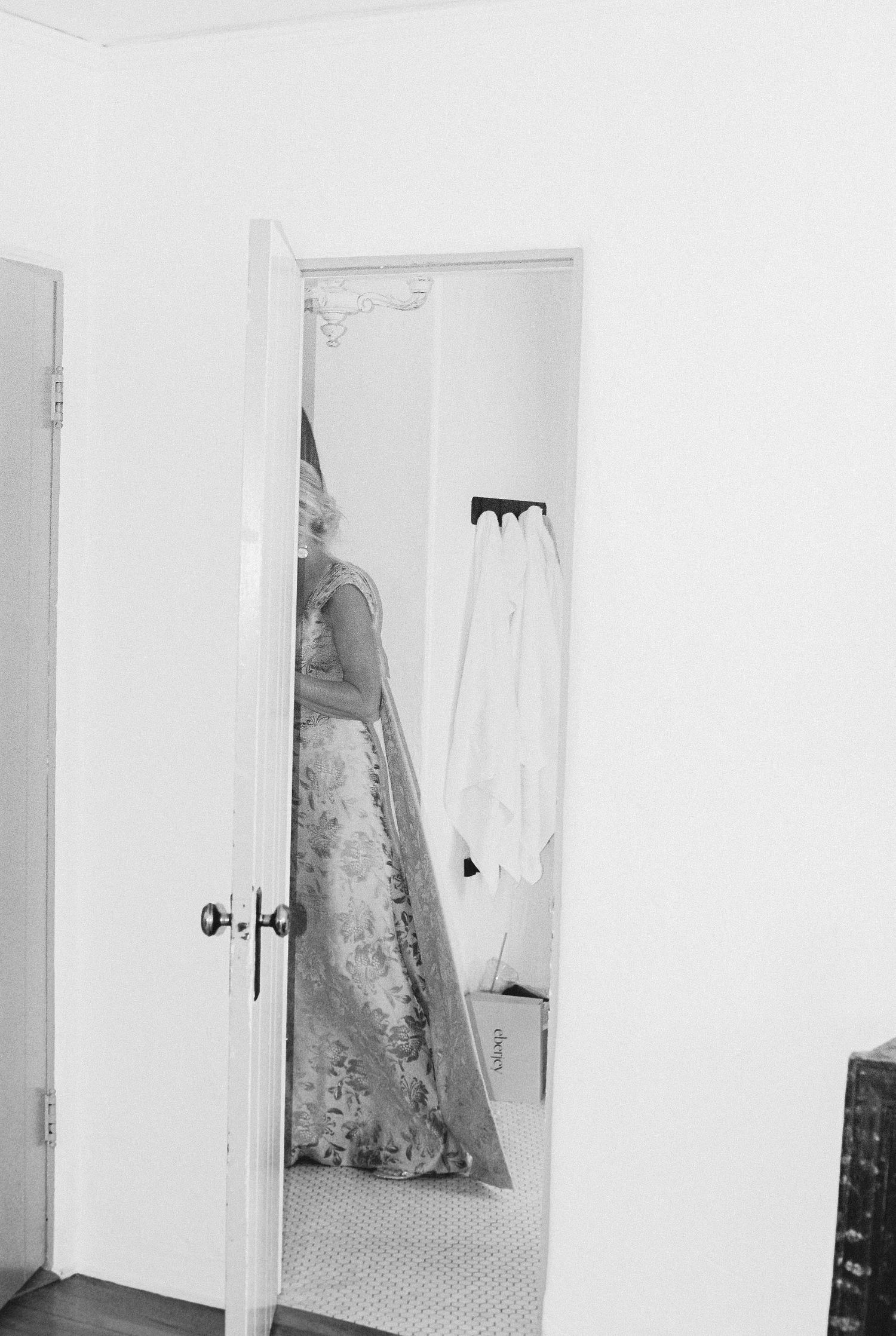 Series of white doorways and walls showing glimpses of a wedding dress hanging.