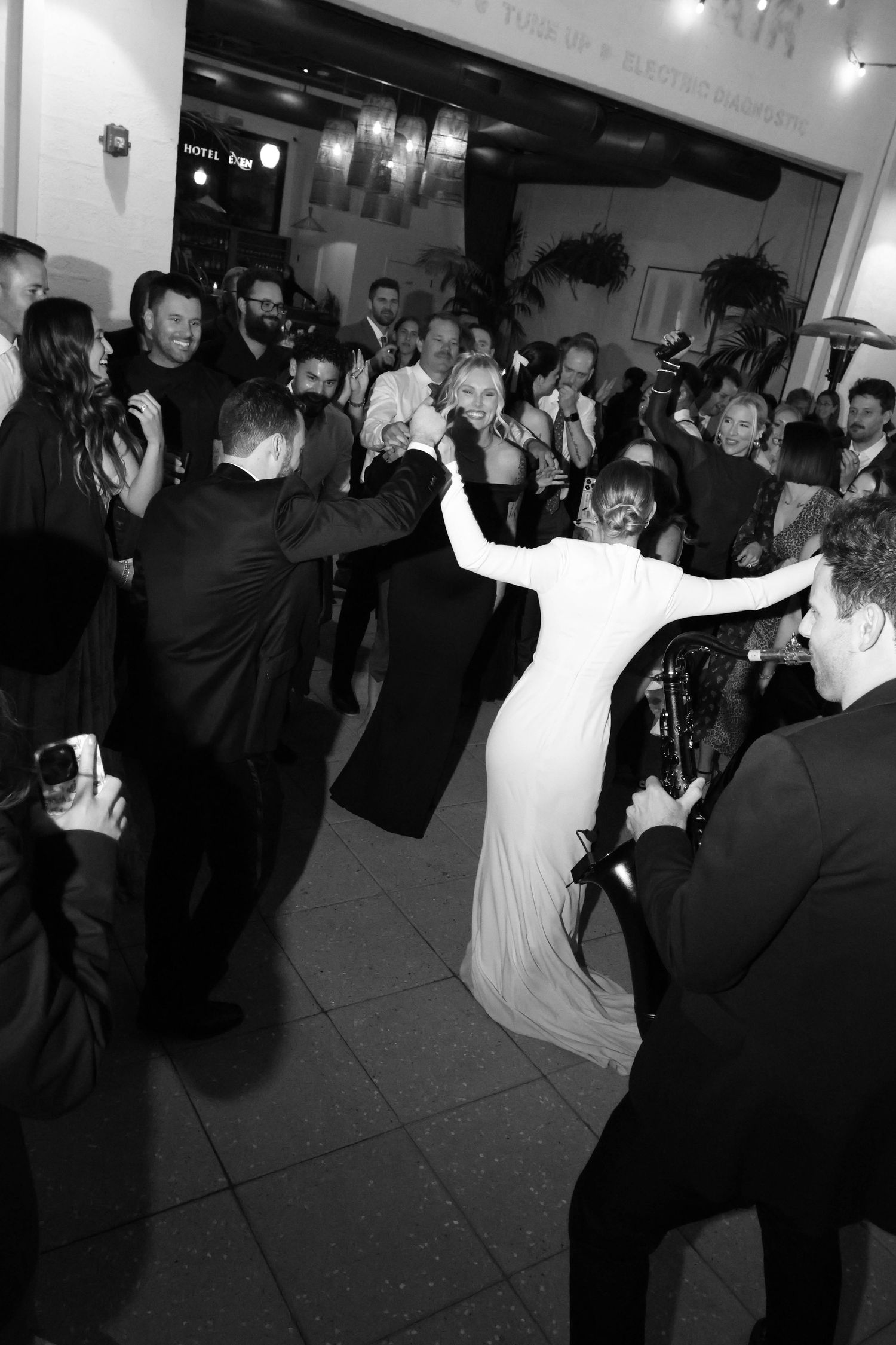 Black and white photo of wedding guests dancing and celebrating on a crowded dance floor.
