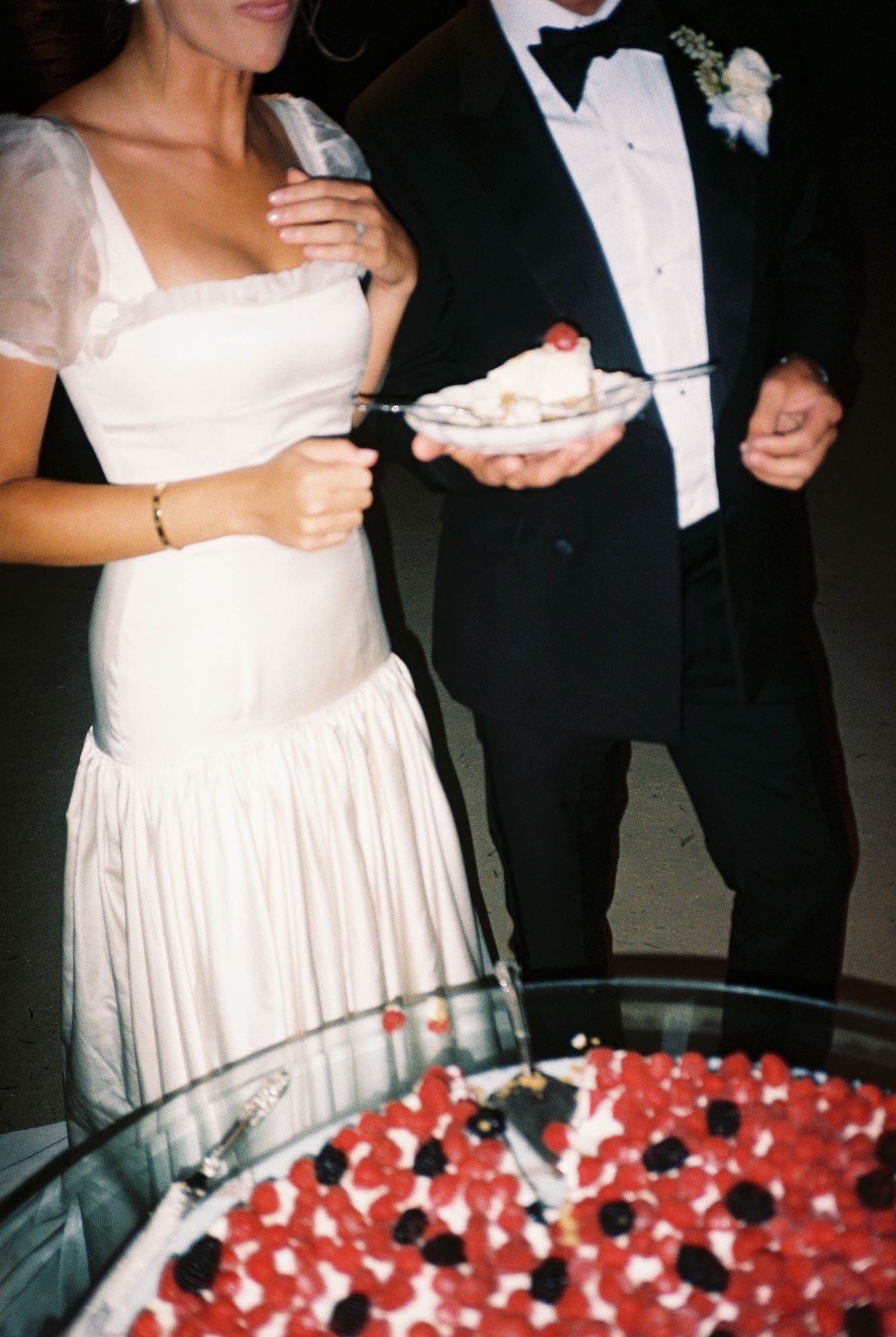 Wedding cake decorated with red berries and white details viewed from above.