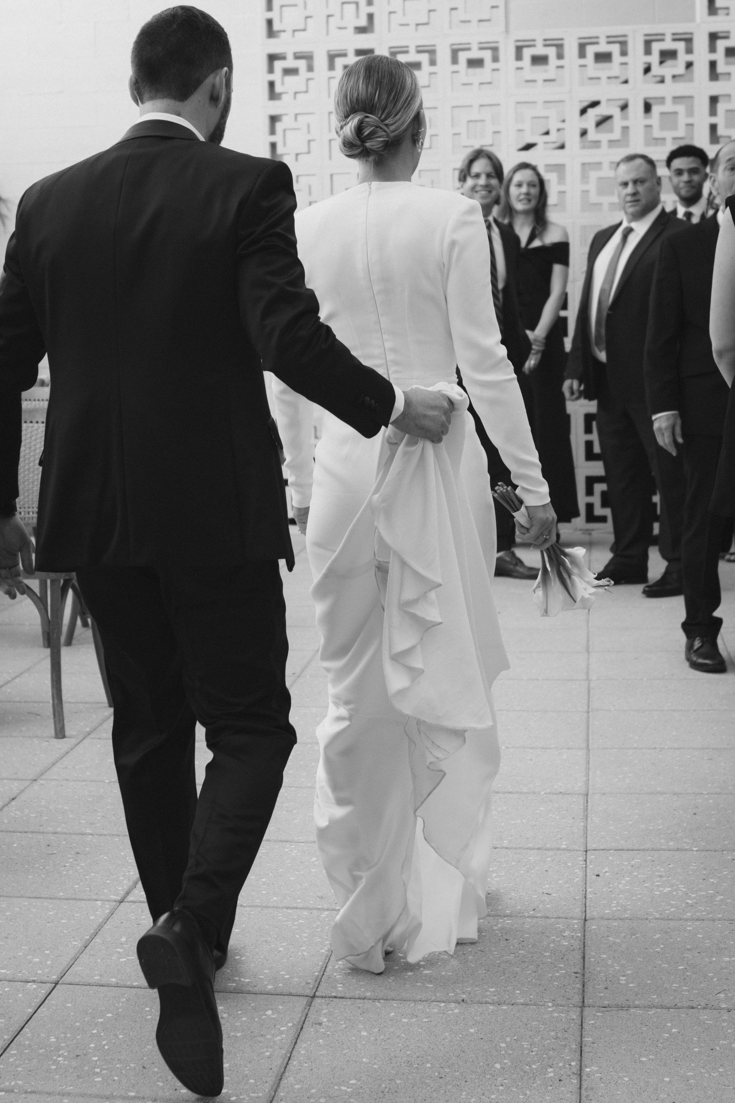 Black and white photo of wedding party walking through modern architectural space.