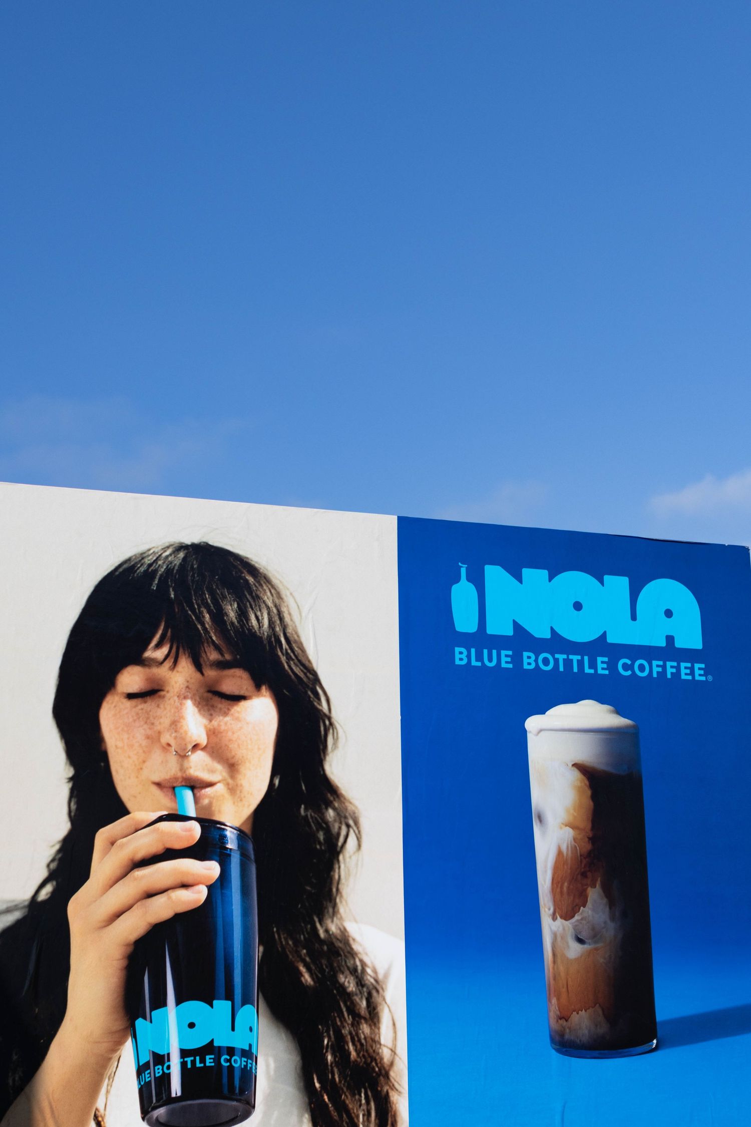 Cold brew coffee drinks in branded cups against a bright blue background.