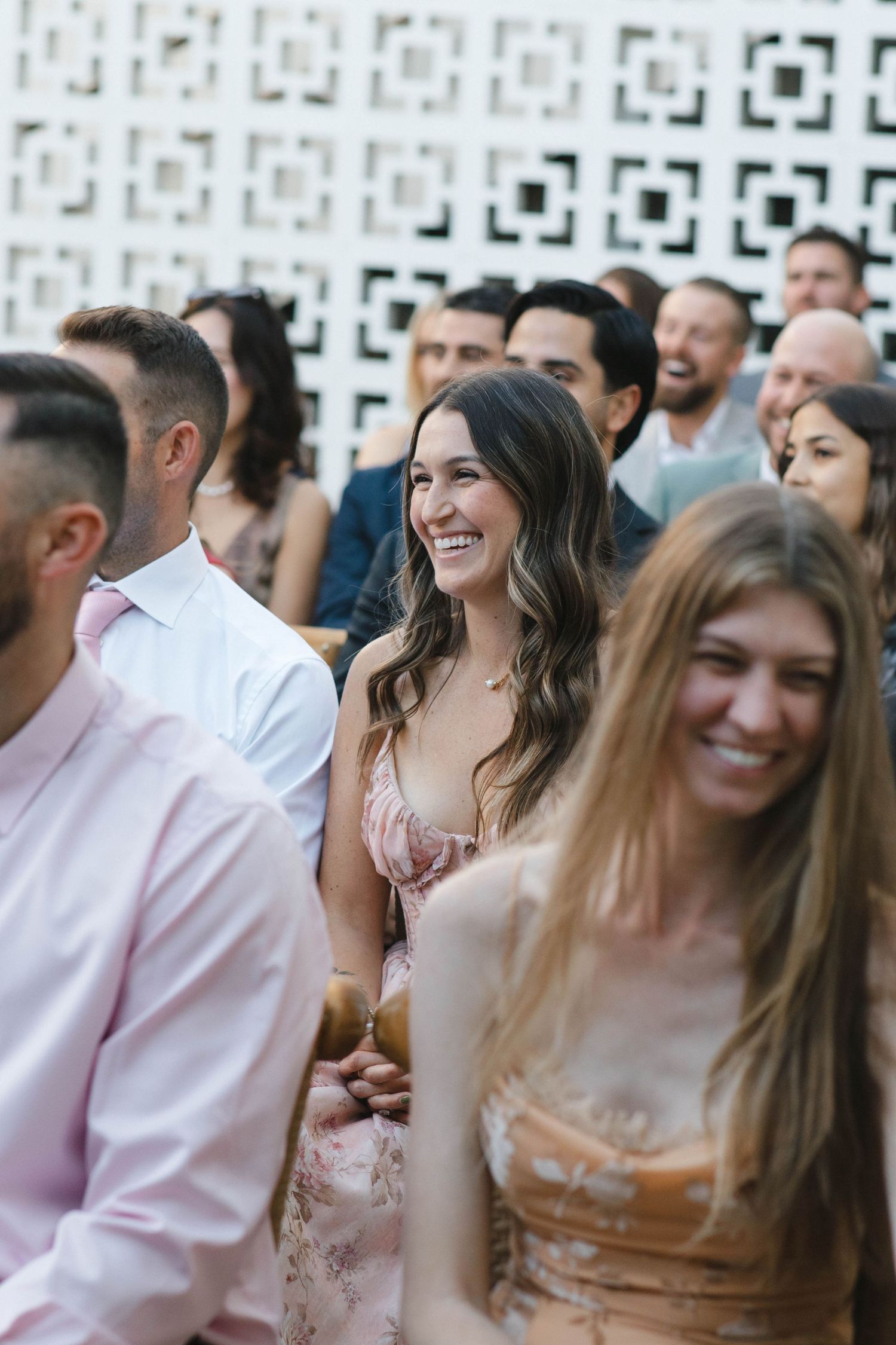 Wedding guests enjoying themselves at an outdoor reception with decorative wall backdrop.