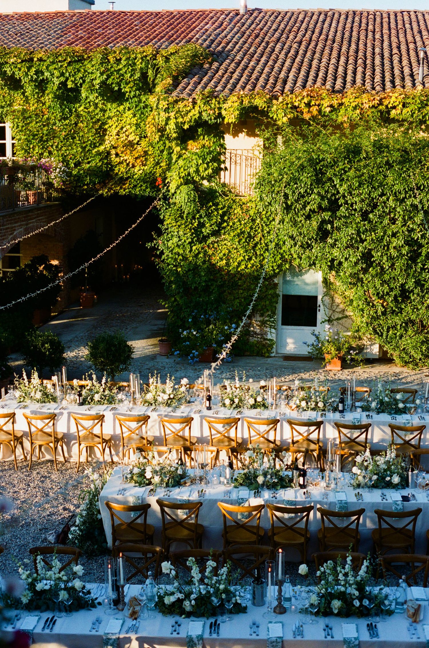 Aerial view of a long wedding reception table setup with string lights and greenery.