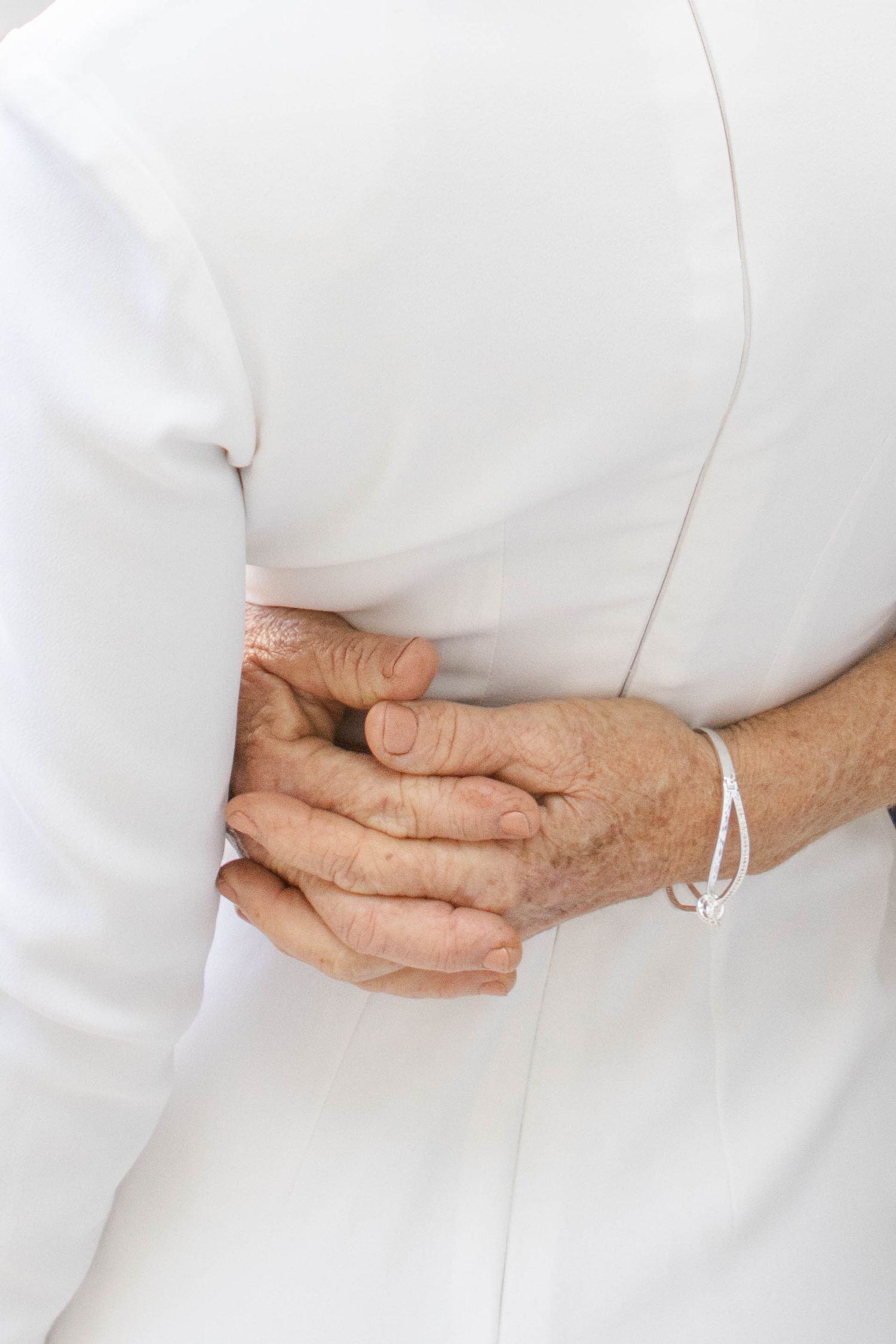 Close-up of hands gently resting against white fabric.