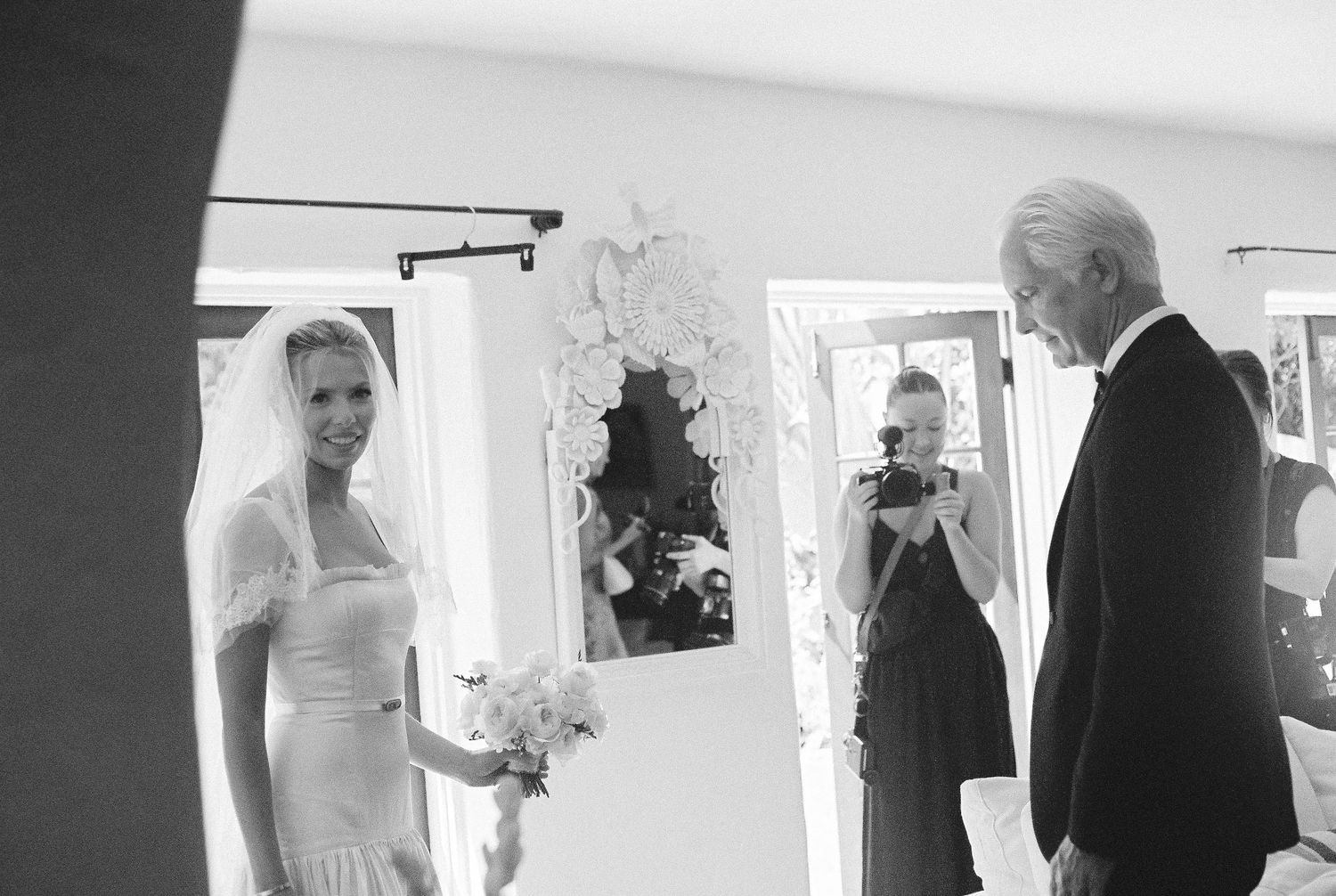 Black and white formal event photography showing guests mingling in an indoor space.