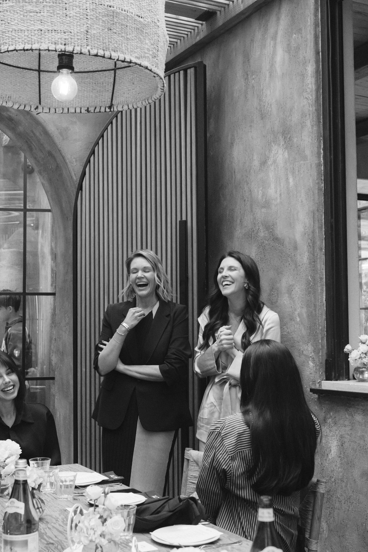 Black and white photo of guests laughing during a social gathering at an outdoor restaurant.