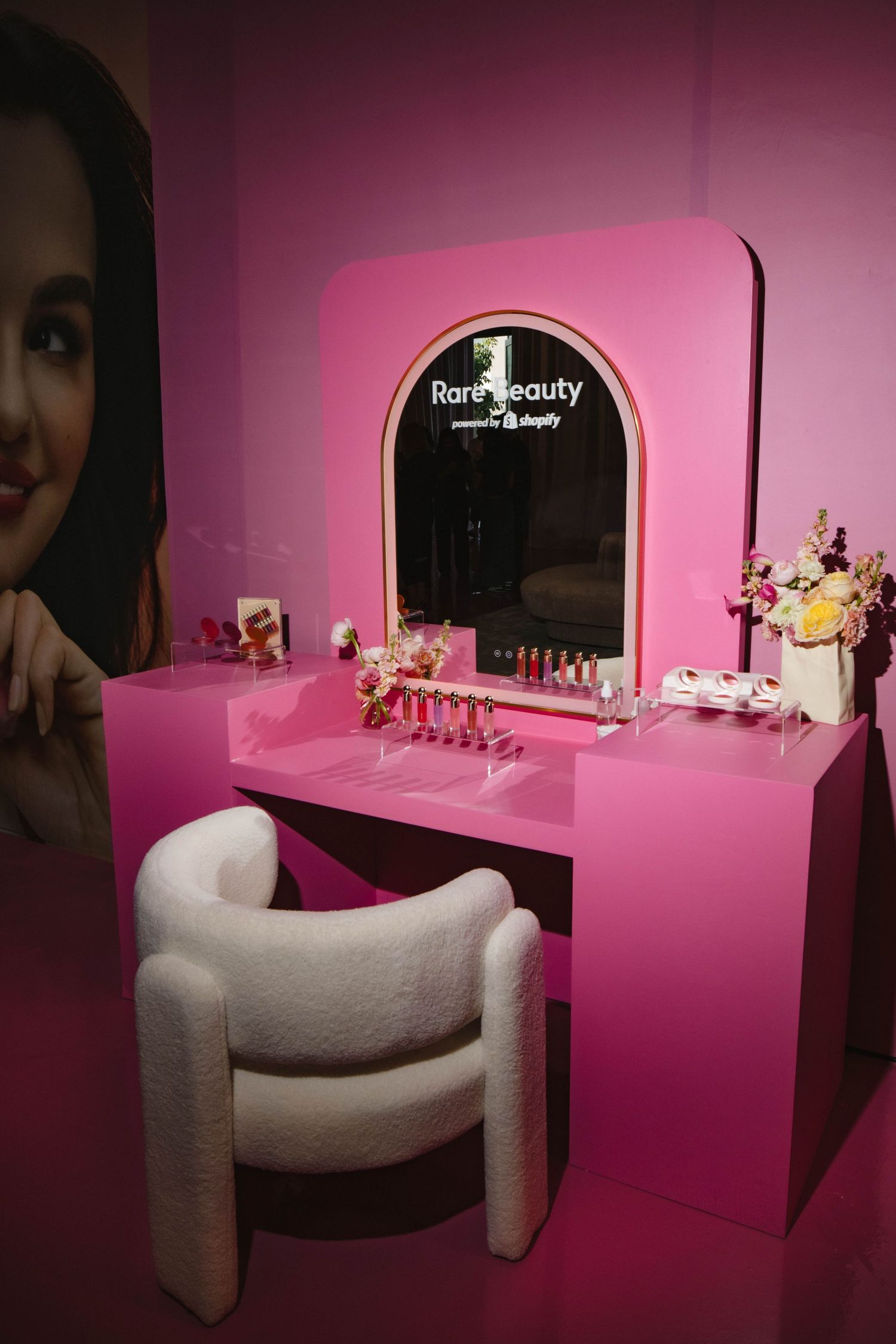 Pink beauty salon interior with curved white seating and vanity mirror displays in a minimalist modern design aesthetic.