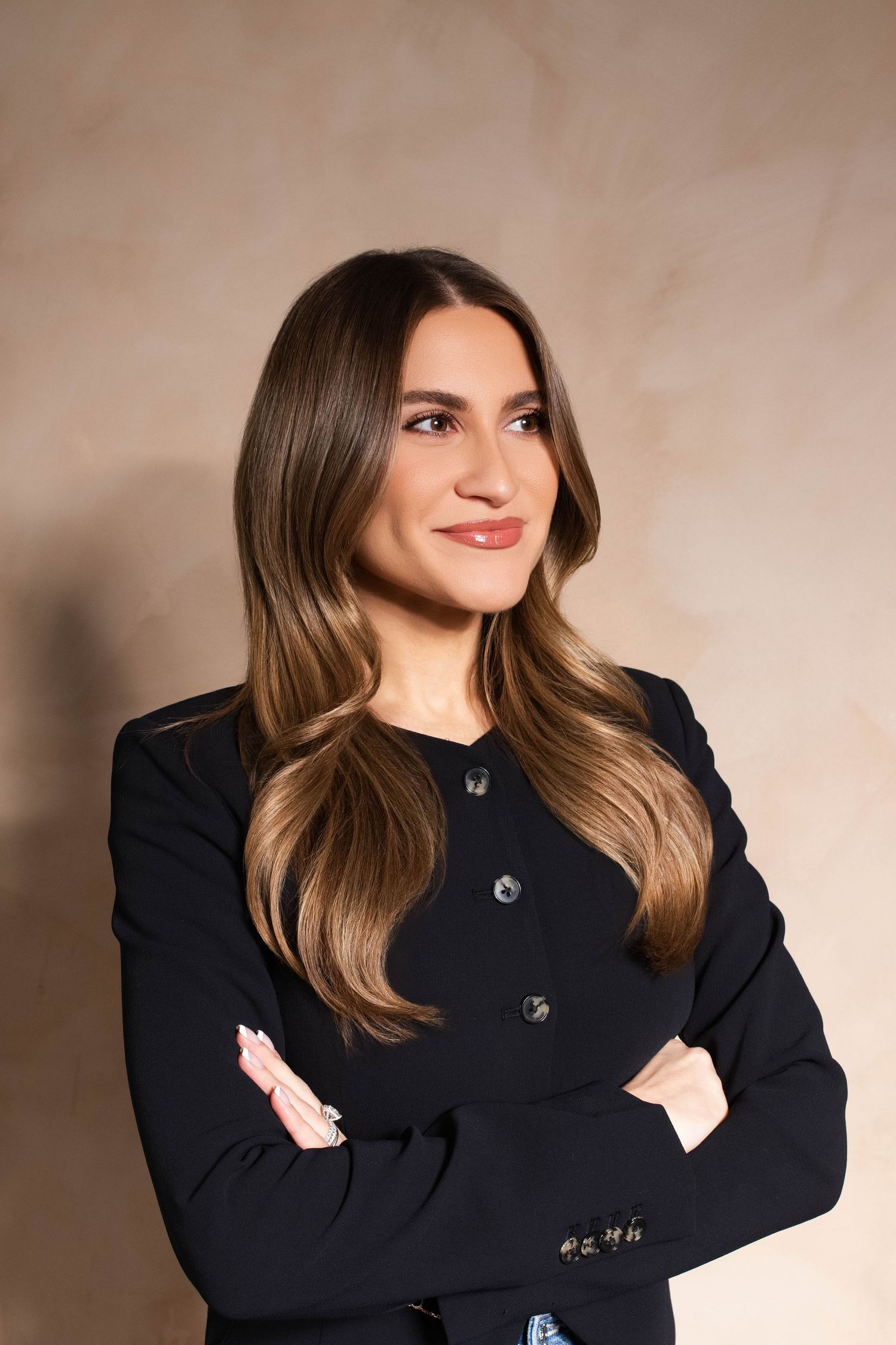 Person wearing black sweater posing against beige background in studio setting.