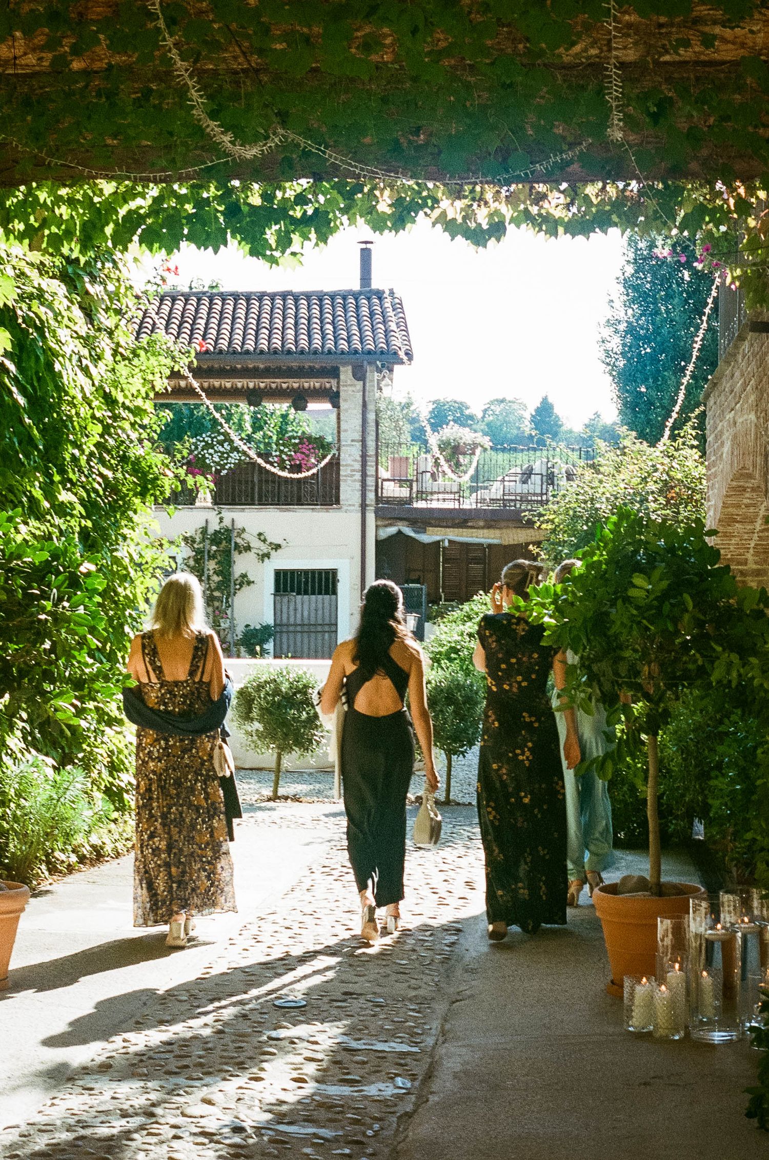 Stone pathway through a Mediterranean garden with sunlit archways and greenery.