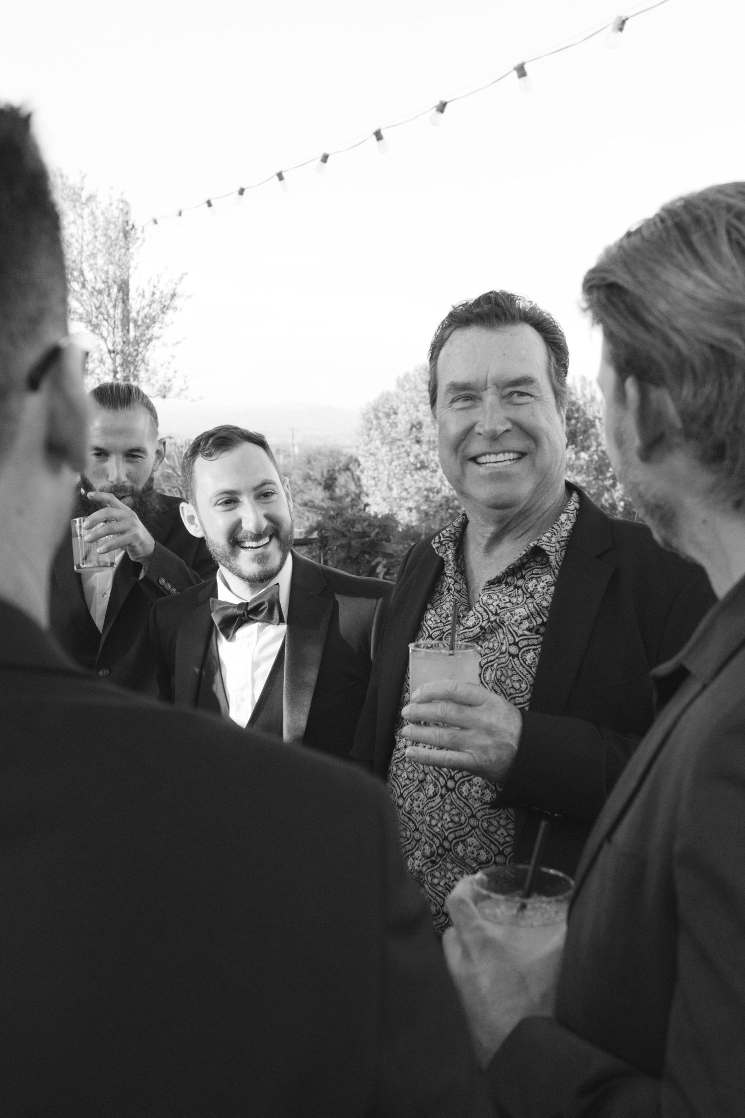A sequence of black and white photos showing people laughing and socializing at a formal gathering.