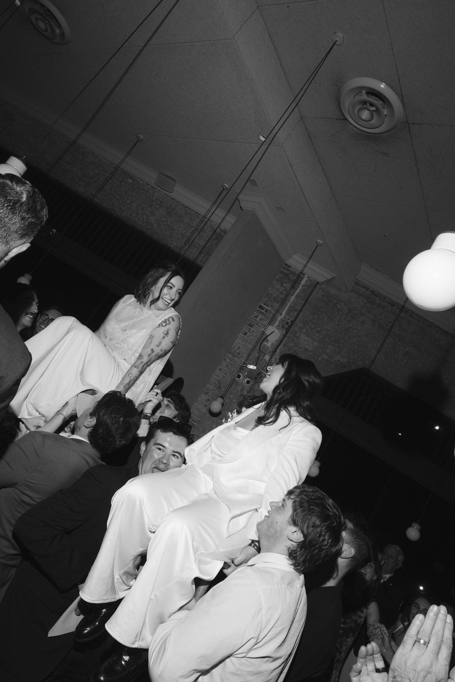 Black and white photo of people dancing and socializing at what appears to be a nightclub or party venue.