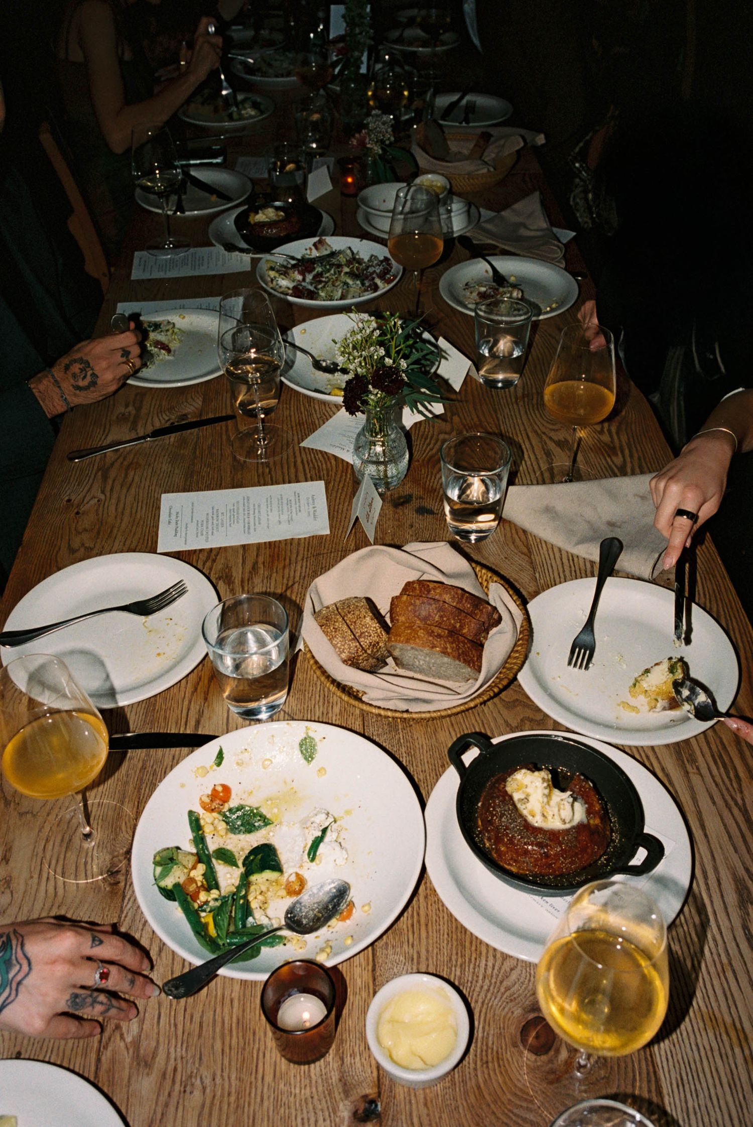 Overhead view of a dinner table with various dishes and drinks spread across a wooden surface.