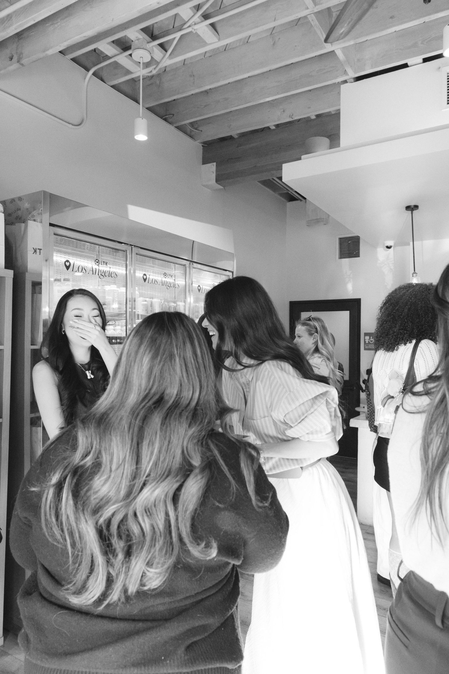 Group gathering in bright indoor space with exposed ceiling beams.