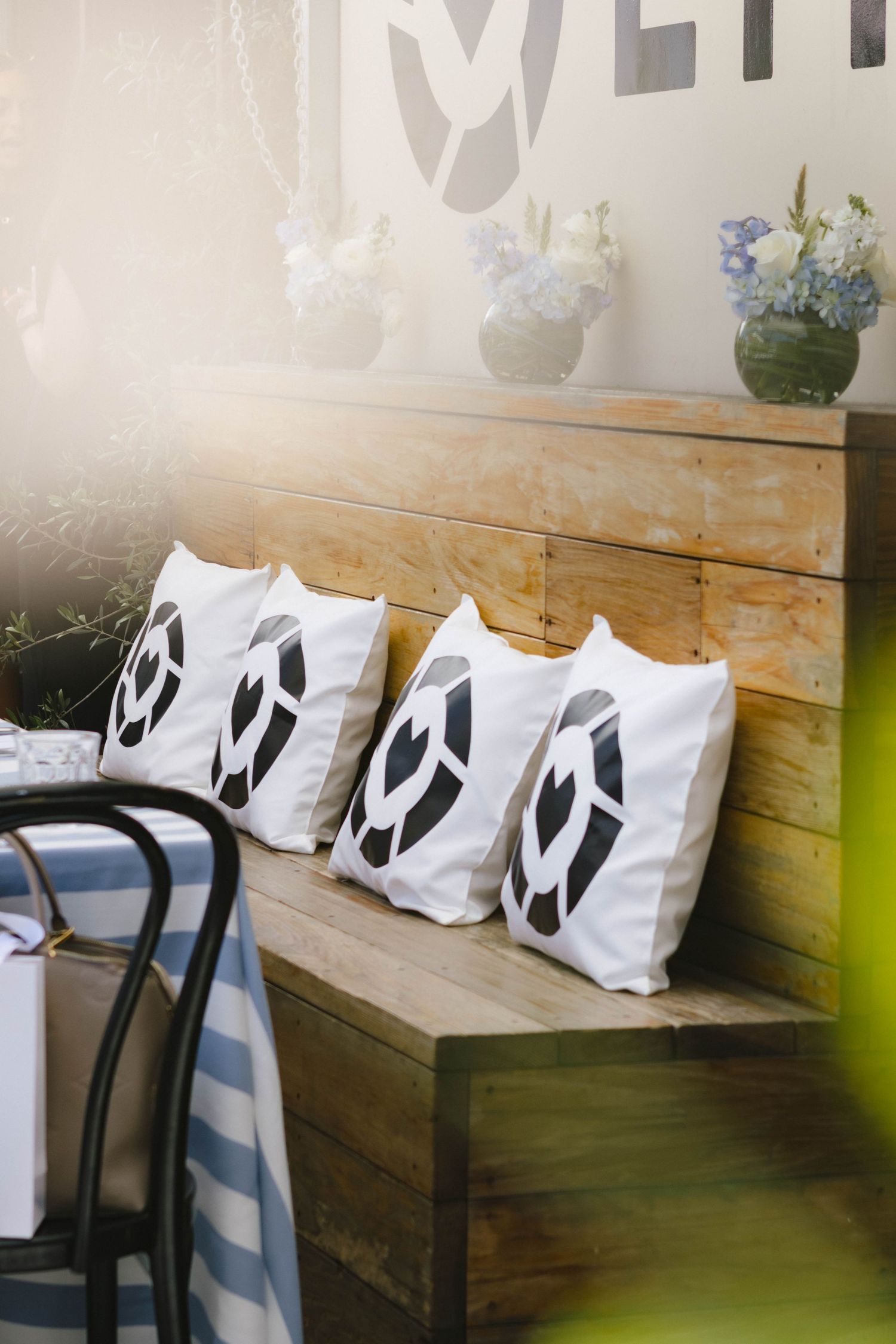 Wooden bench seating with white pillows featuring black logo designs in a modern interior space.