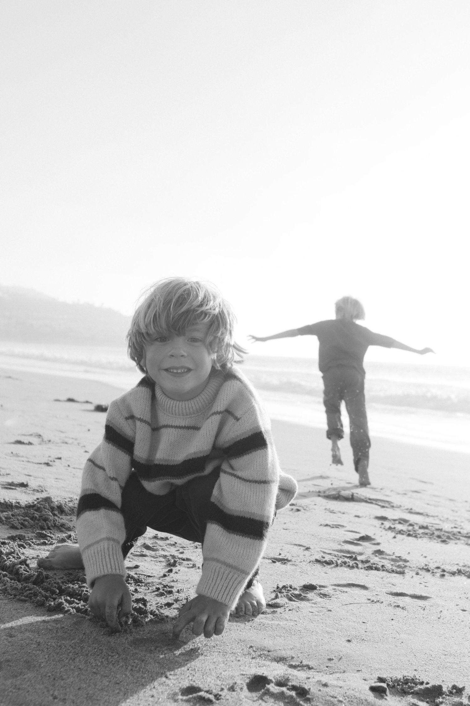 Children playing on a beach at sunset with silhouettes against the bright sky.