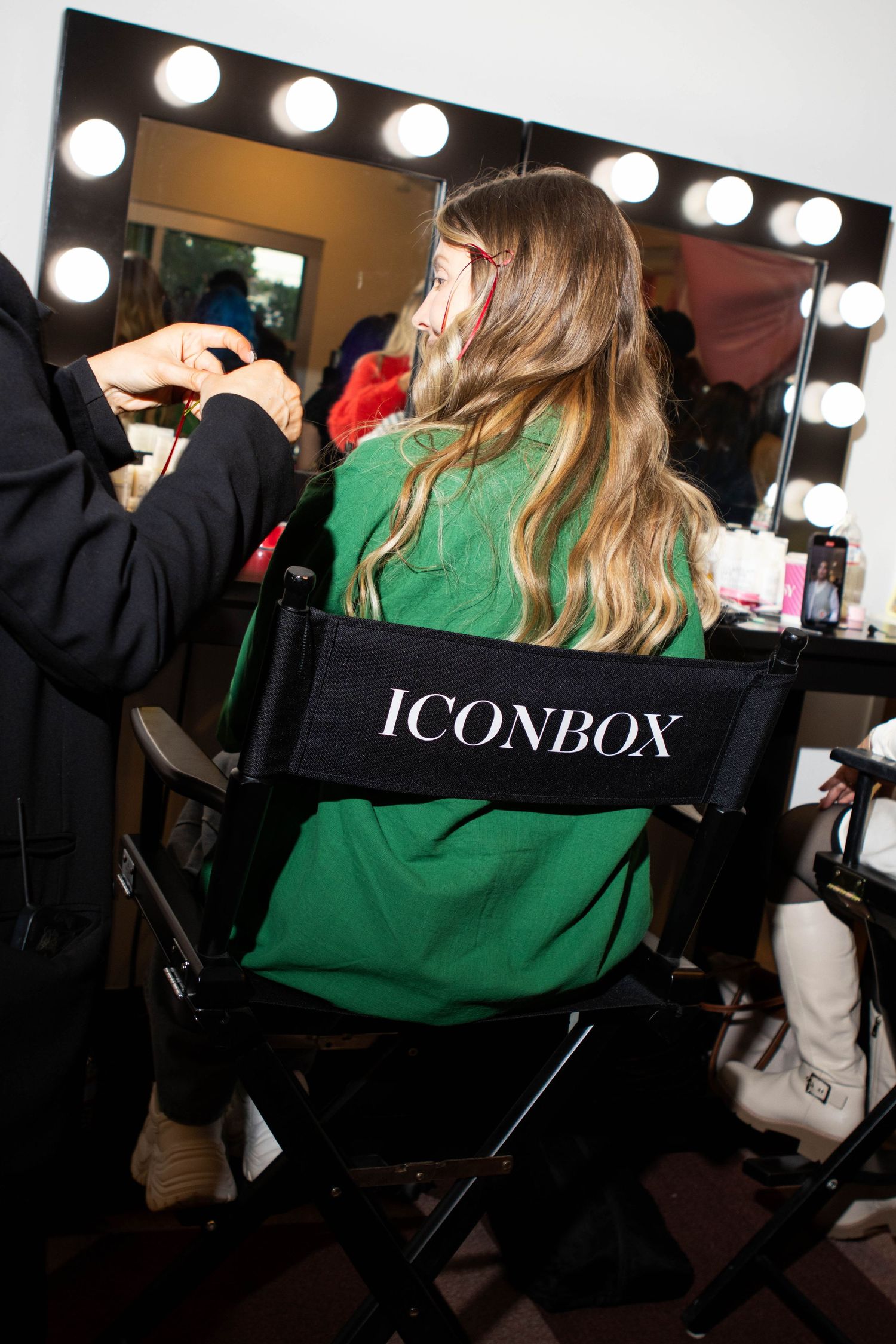 Behind-the-scenes makeup preparation at a vanity with ICONBOX director's chair.