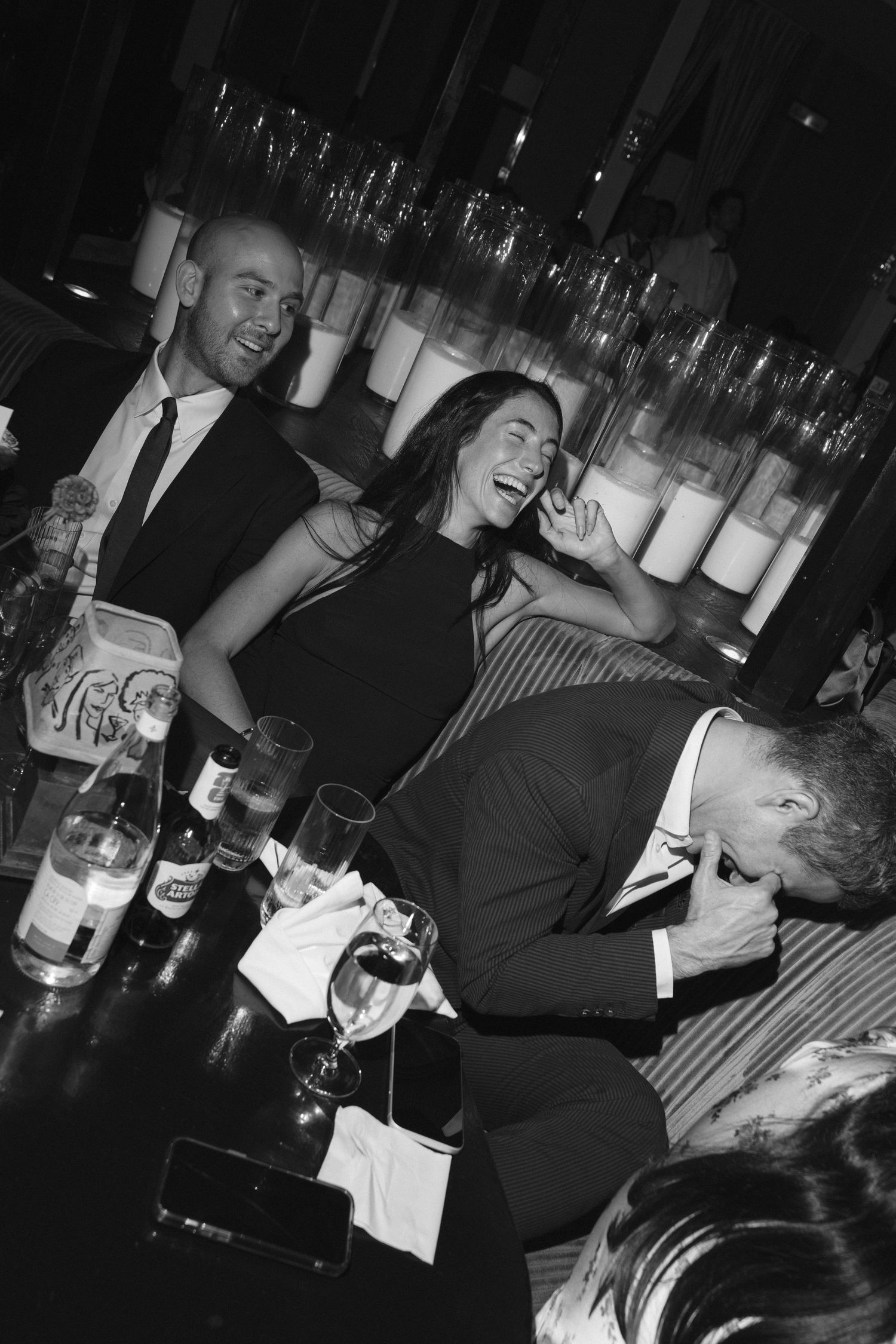 Black and white photo of elegantly dressed people laughing and socializing at a upscale bar or nightclub event.