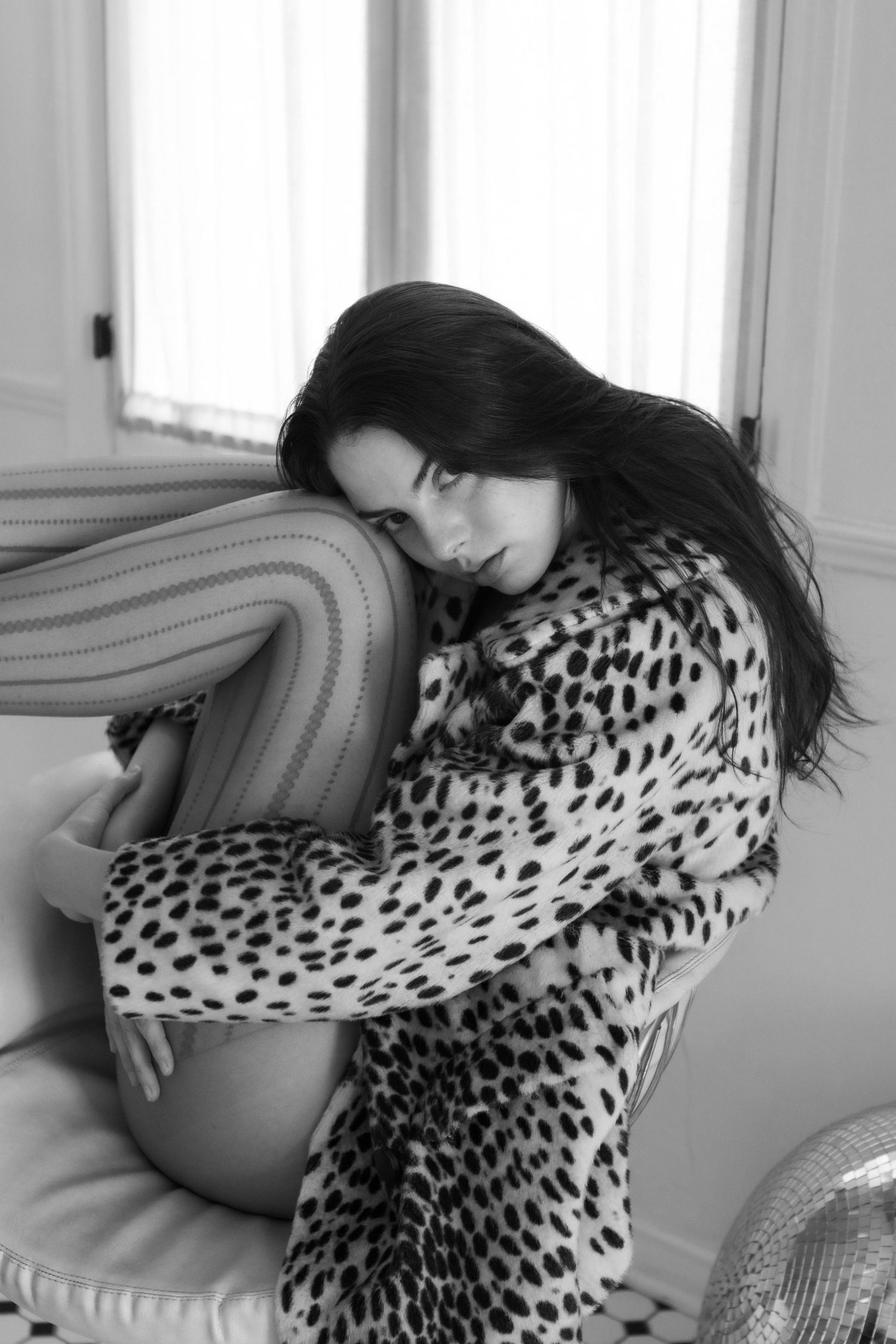 A series of black and white fashion photos showing a person in a leopard print top reclining on a sofa.