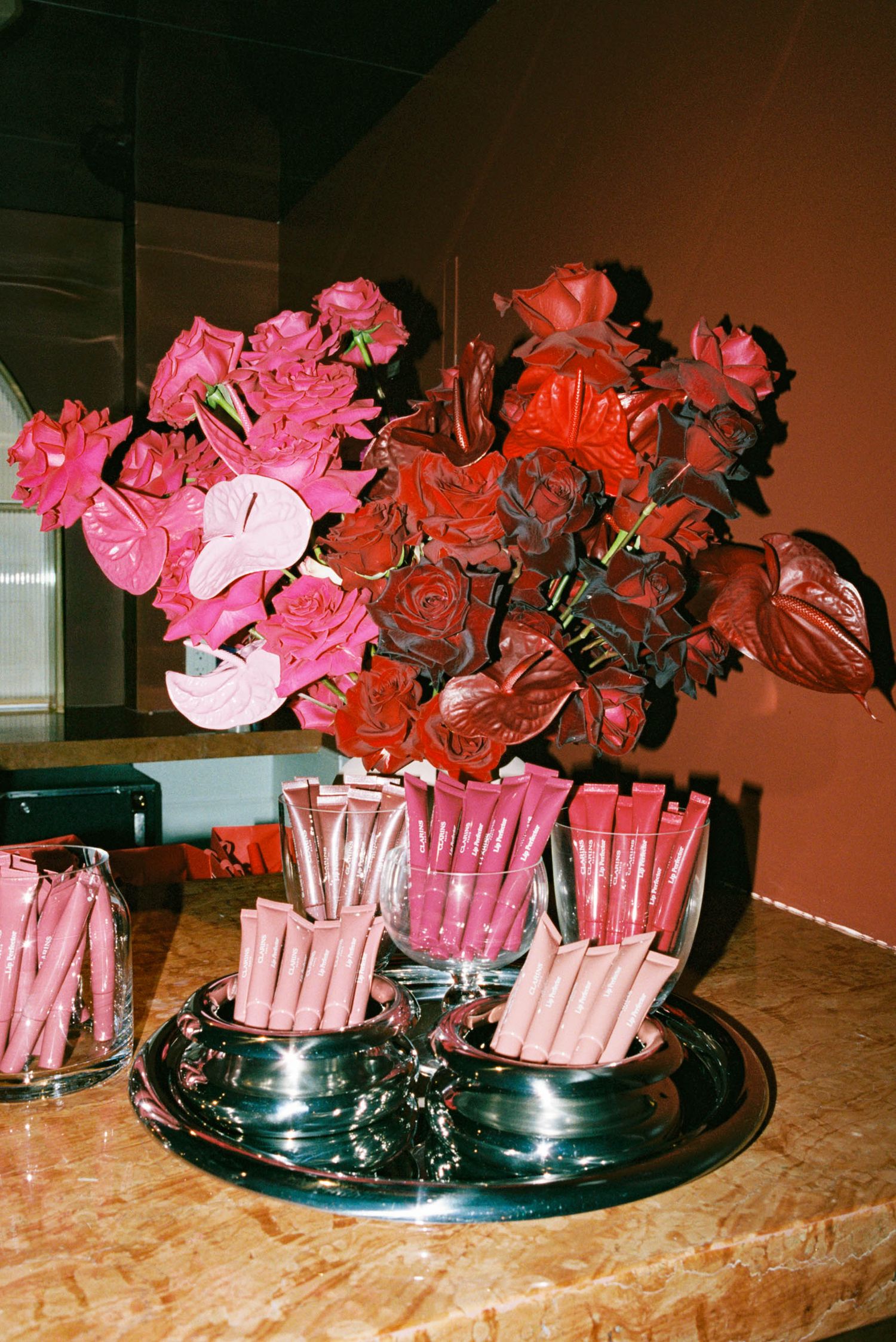 Pink and red roses arranged in glass vases on a marble countertop create an elegant floral display.