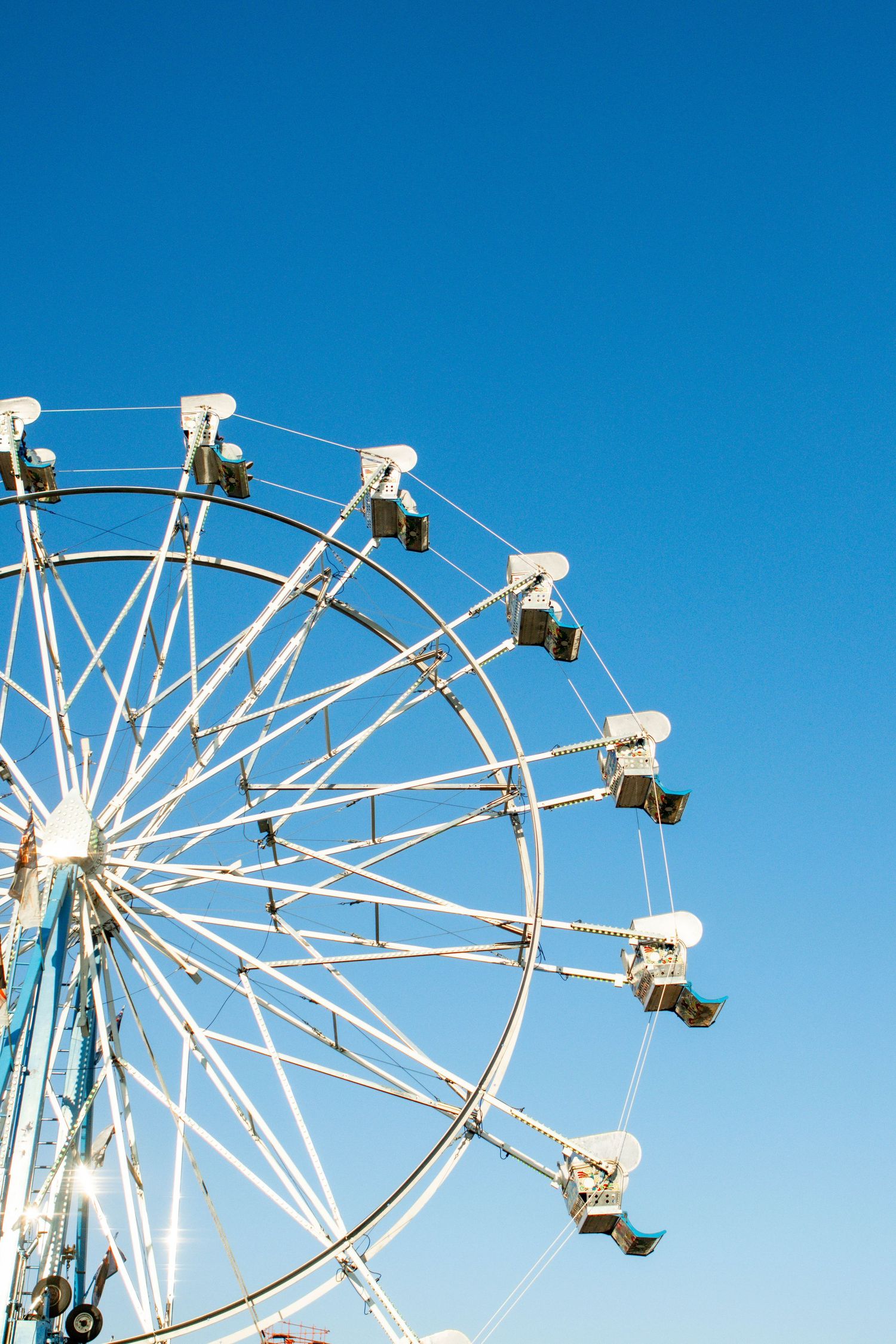 White ferris wheel segments against a vibrant blue sky.