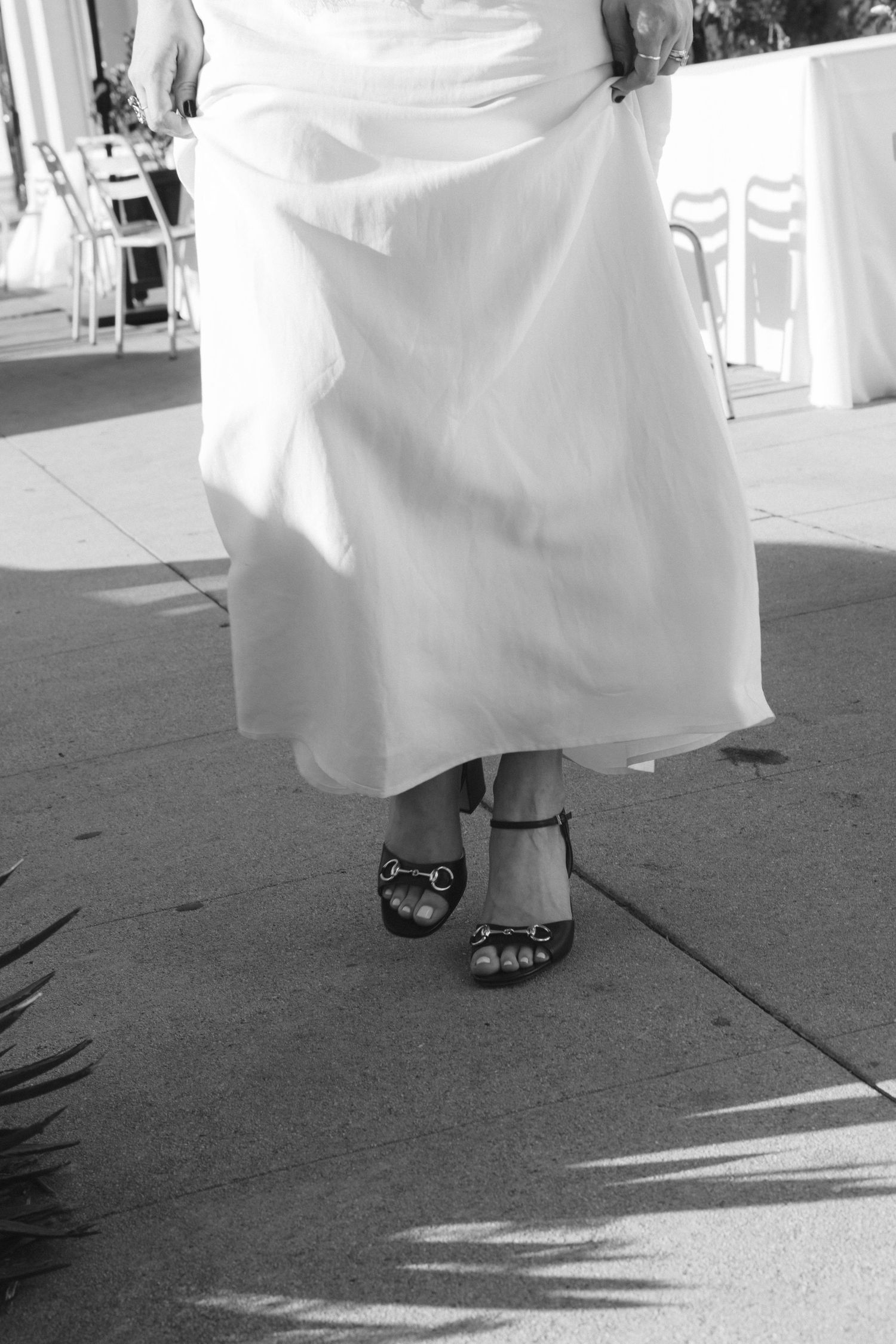 Close-up shot of white wedding dress and shoes on a sunny day.
