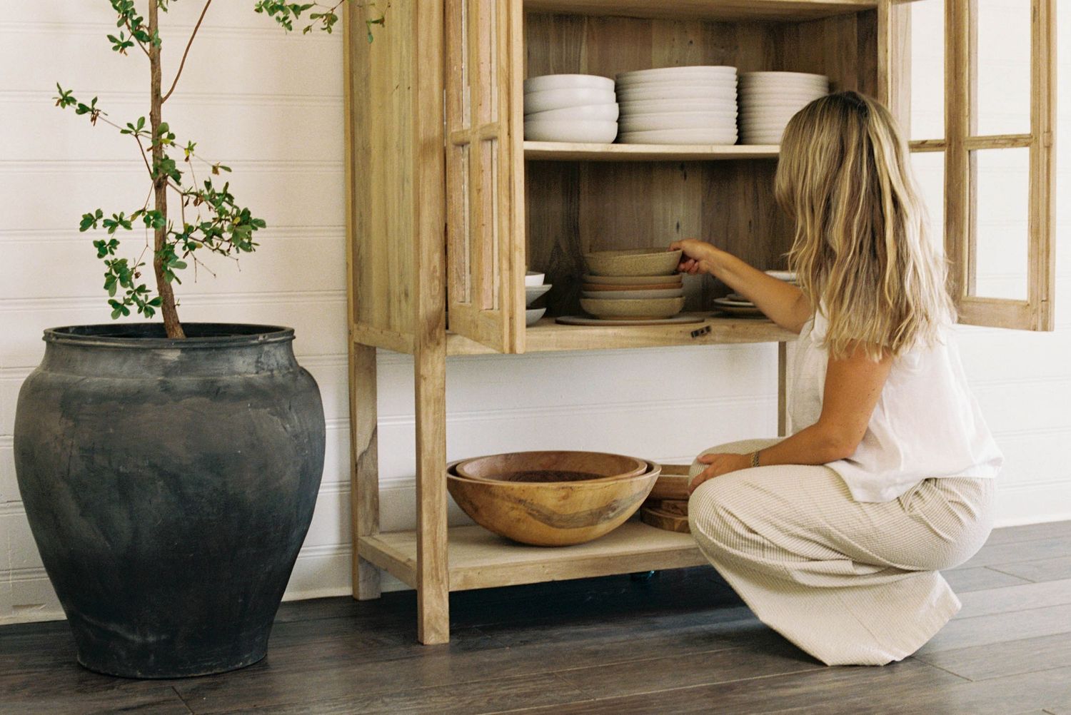 Rustic pottery vessels and ceramic bowls displayed on wooden shelving in a minimalist interior design setting.