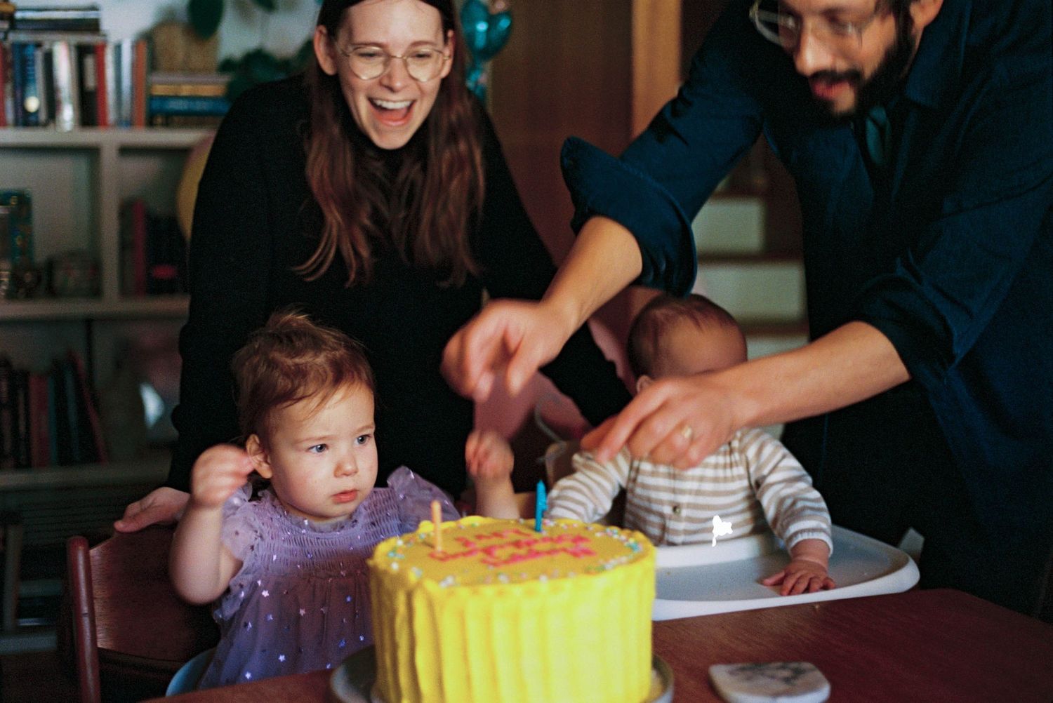 A birthday celebration with a bright yellow cake on a table.