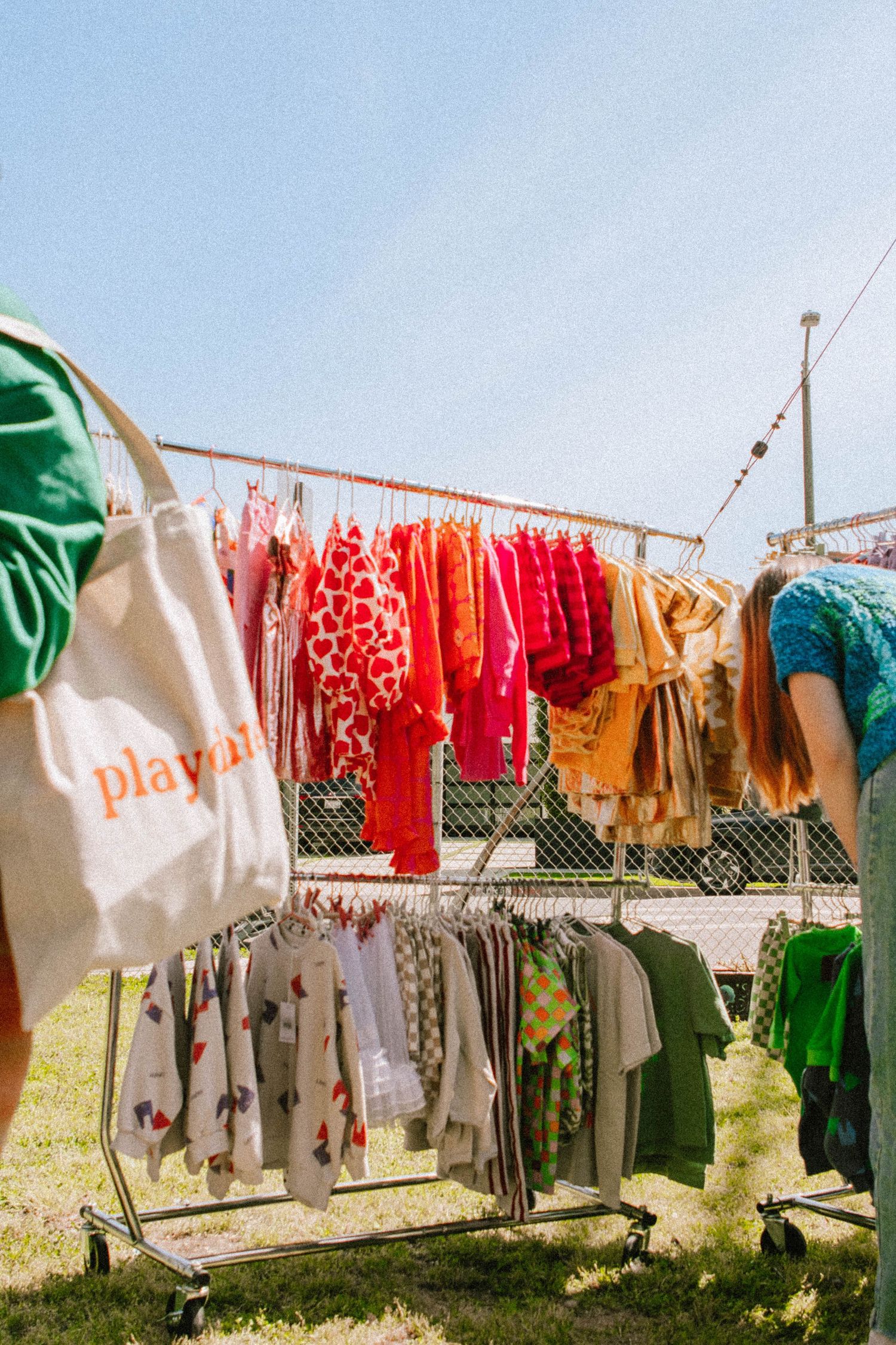 Colorful clothing and textiles hanging on a clothesline outdoors against blue sky.