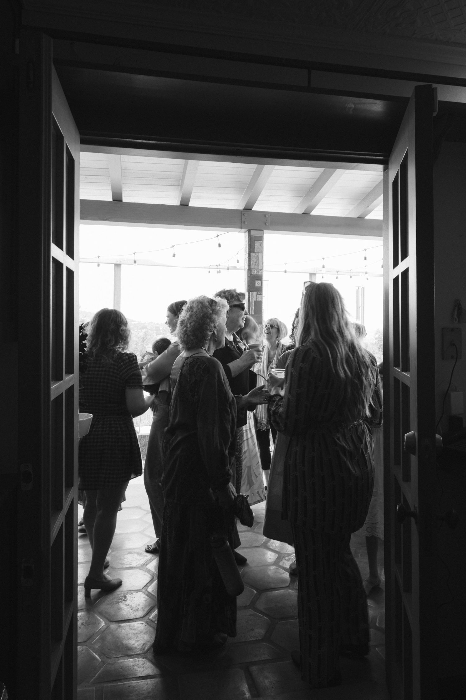 Silhouettes of people gathering in a dark doorway or entrance with light streaming in from outside.