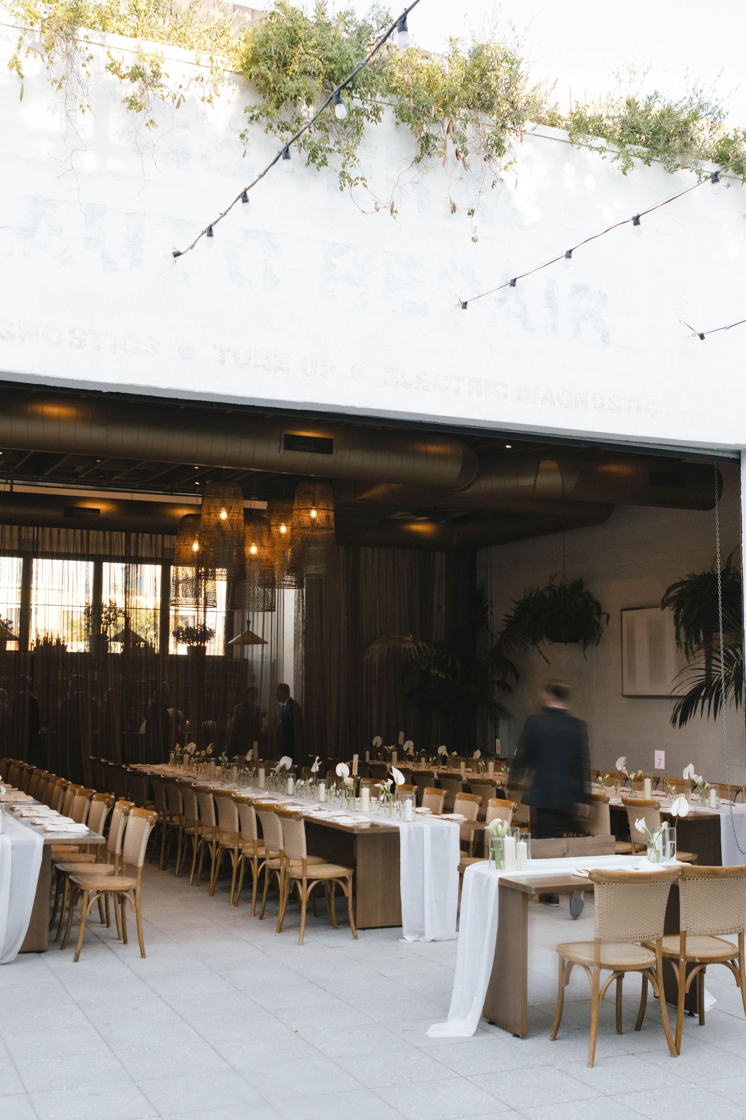 Modern wedding reception venue with long tables and string lights creating an intimate atmosphere.