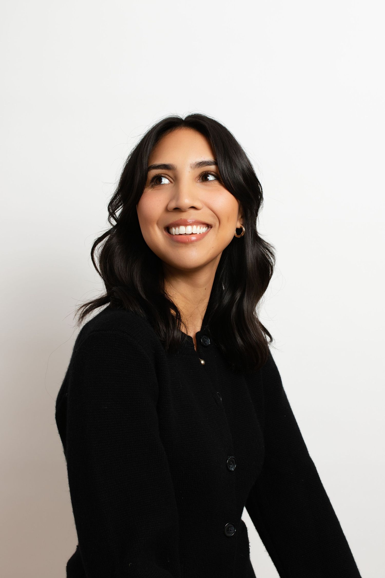 Studio portraits of person in black hoodie against white background.