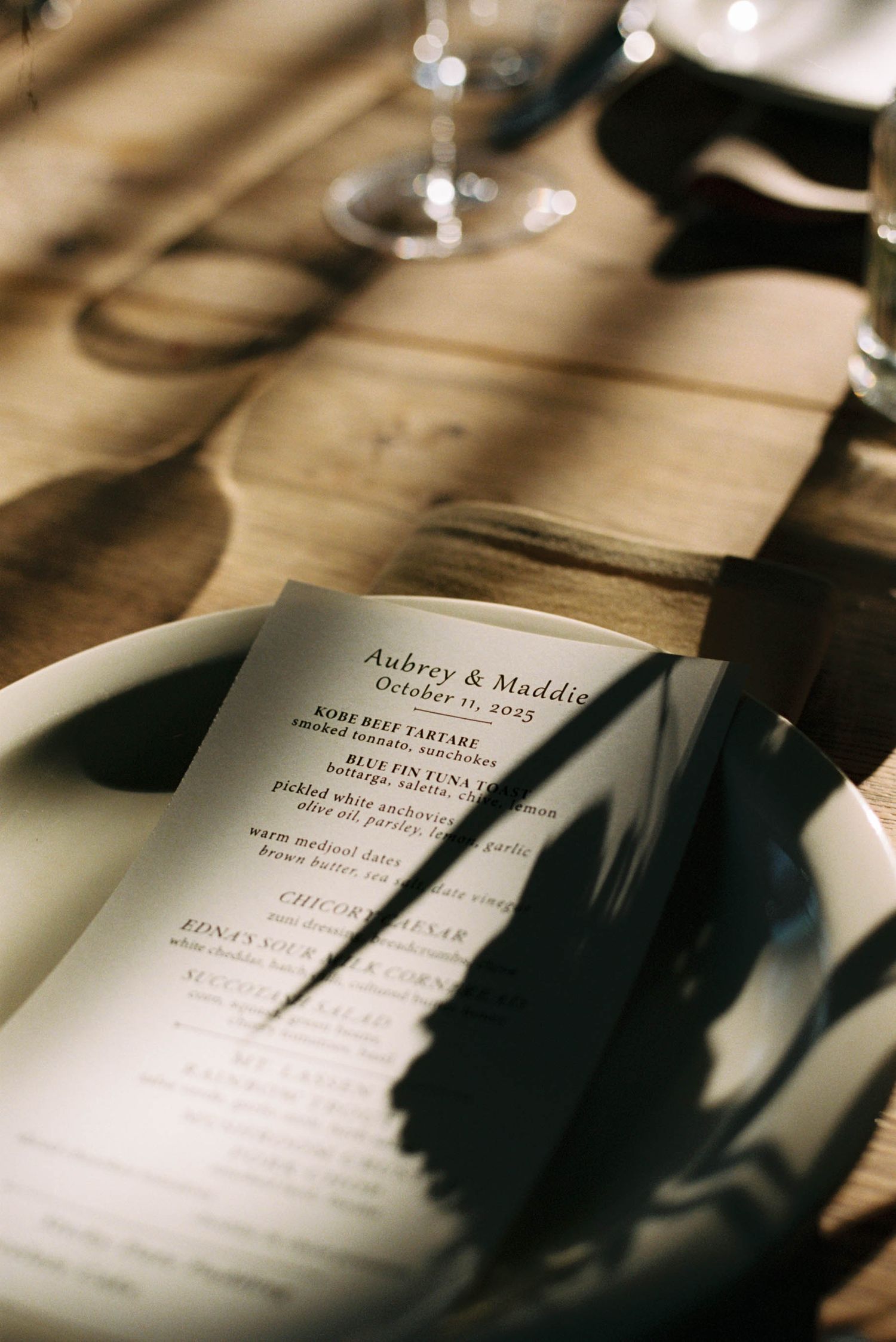 Wedding invitation details shown in soft focus with blurred text and elegant typography on cream colored paper.