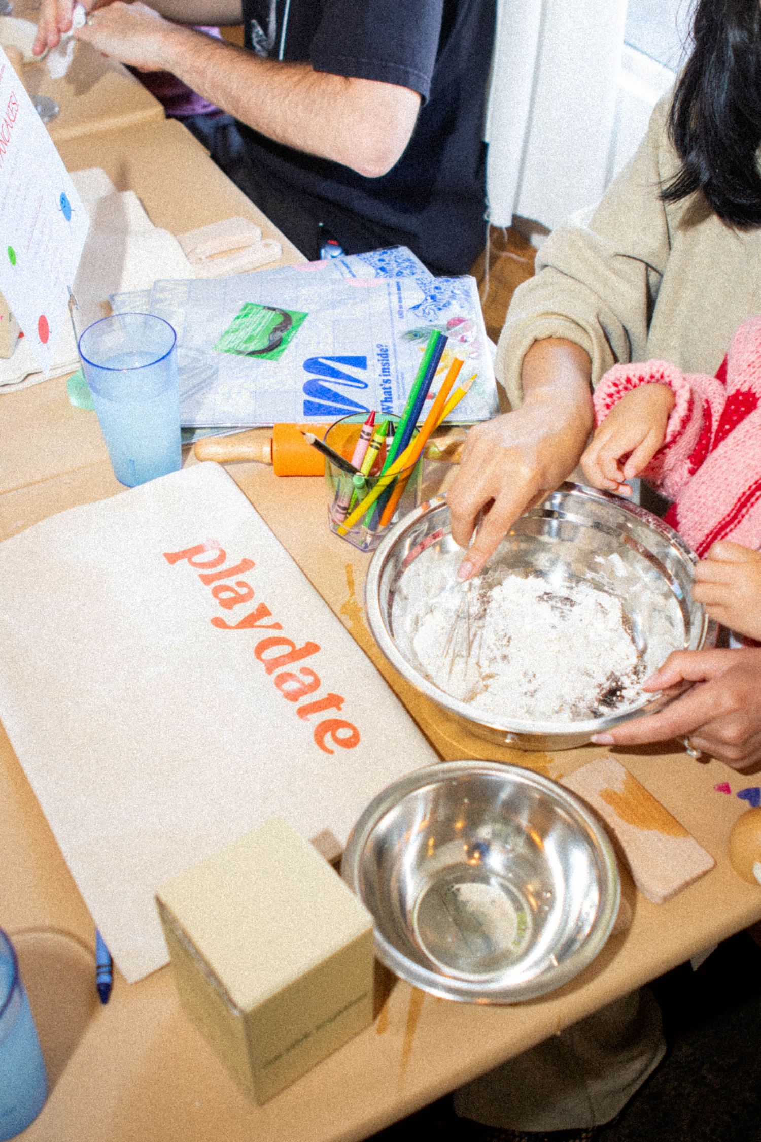People working together at a table with craft supplies and materials for a creative workshop activity.