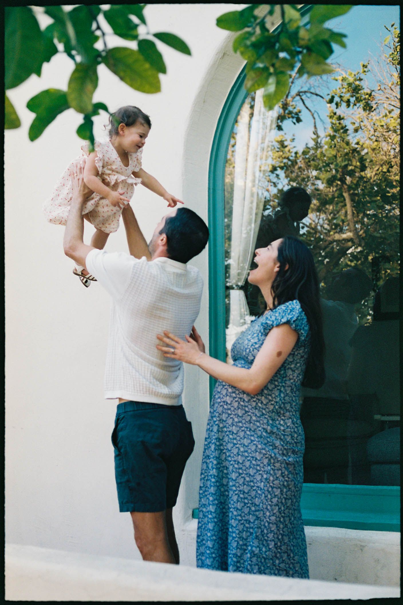 A series of outdoor family portraits taken against a white wall with turquoise trim.