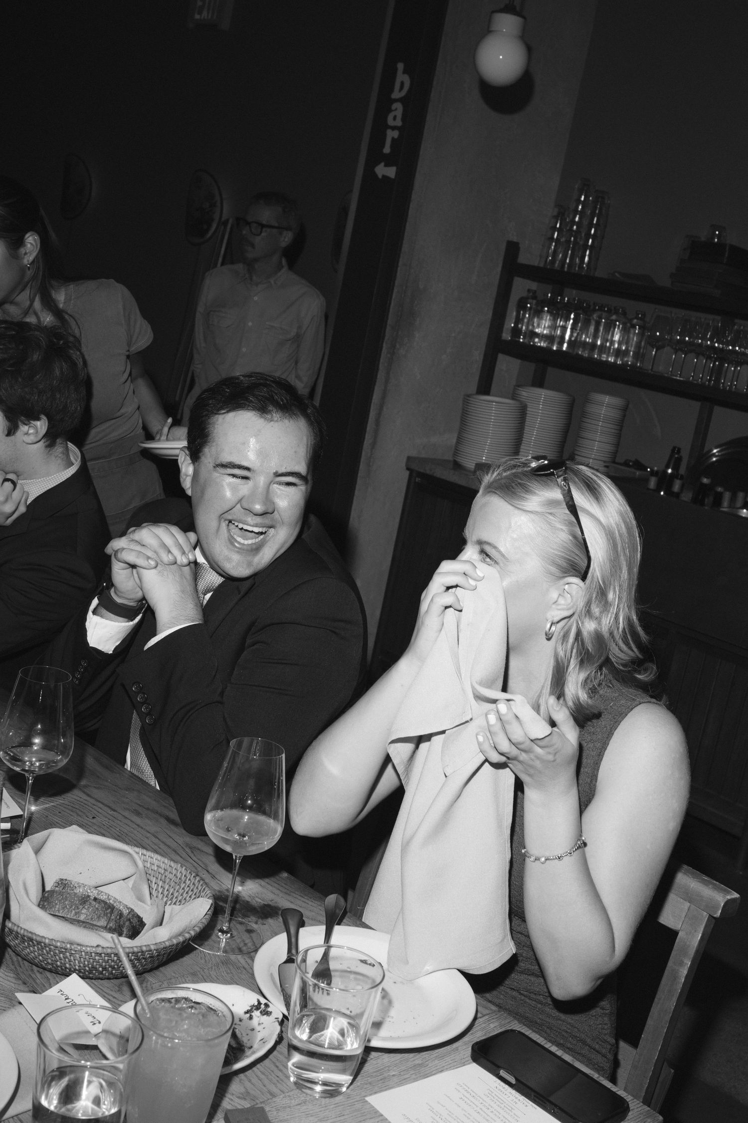 Friends laughing and enjoying drinks together at a dimly lit bar.