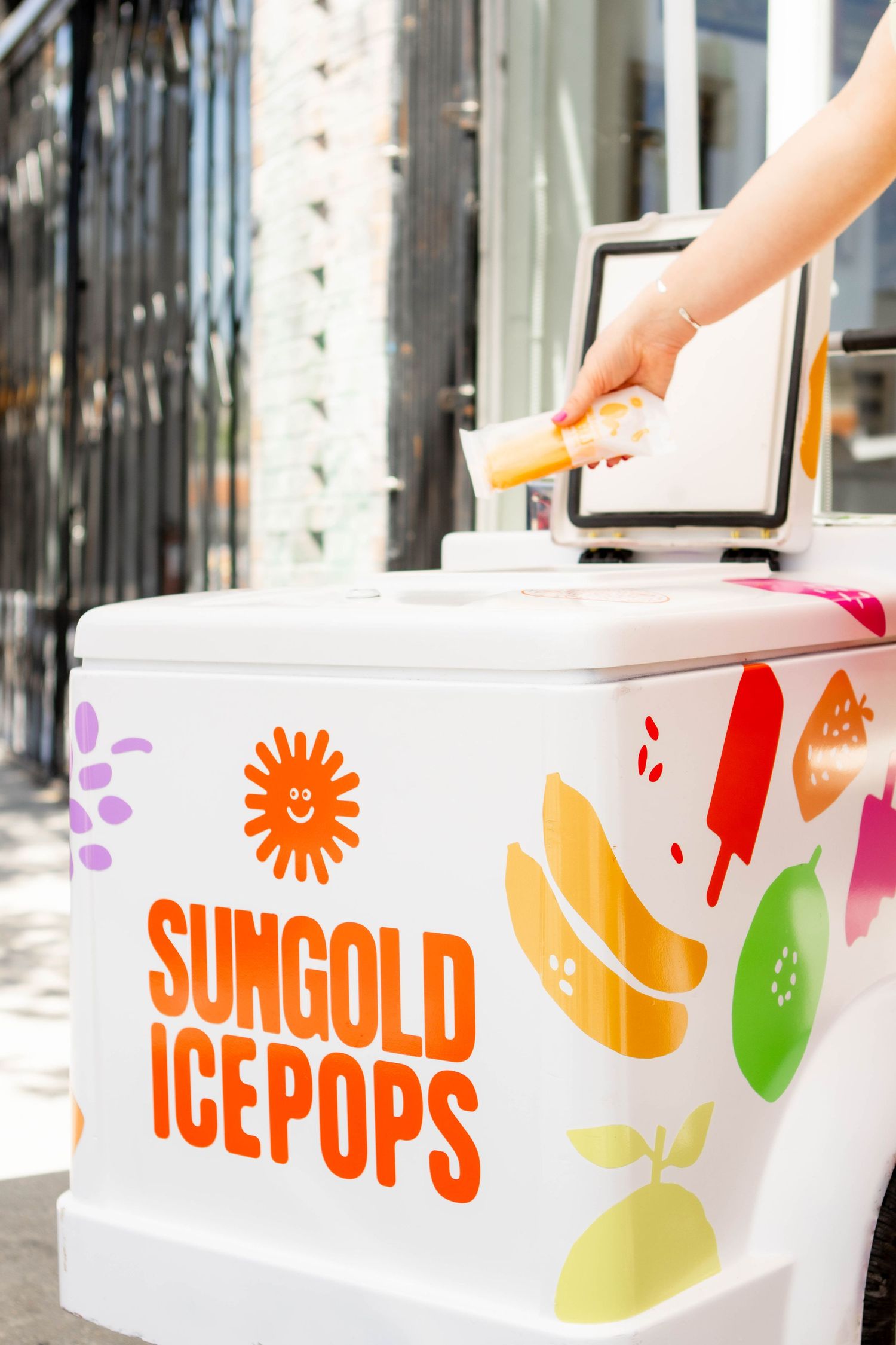 White cooler with colorful Sungold Ice Pops branding and fruit designs.