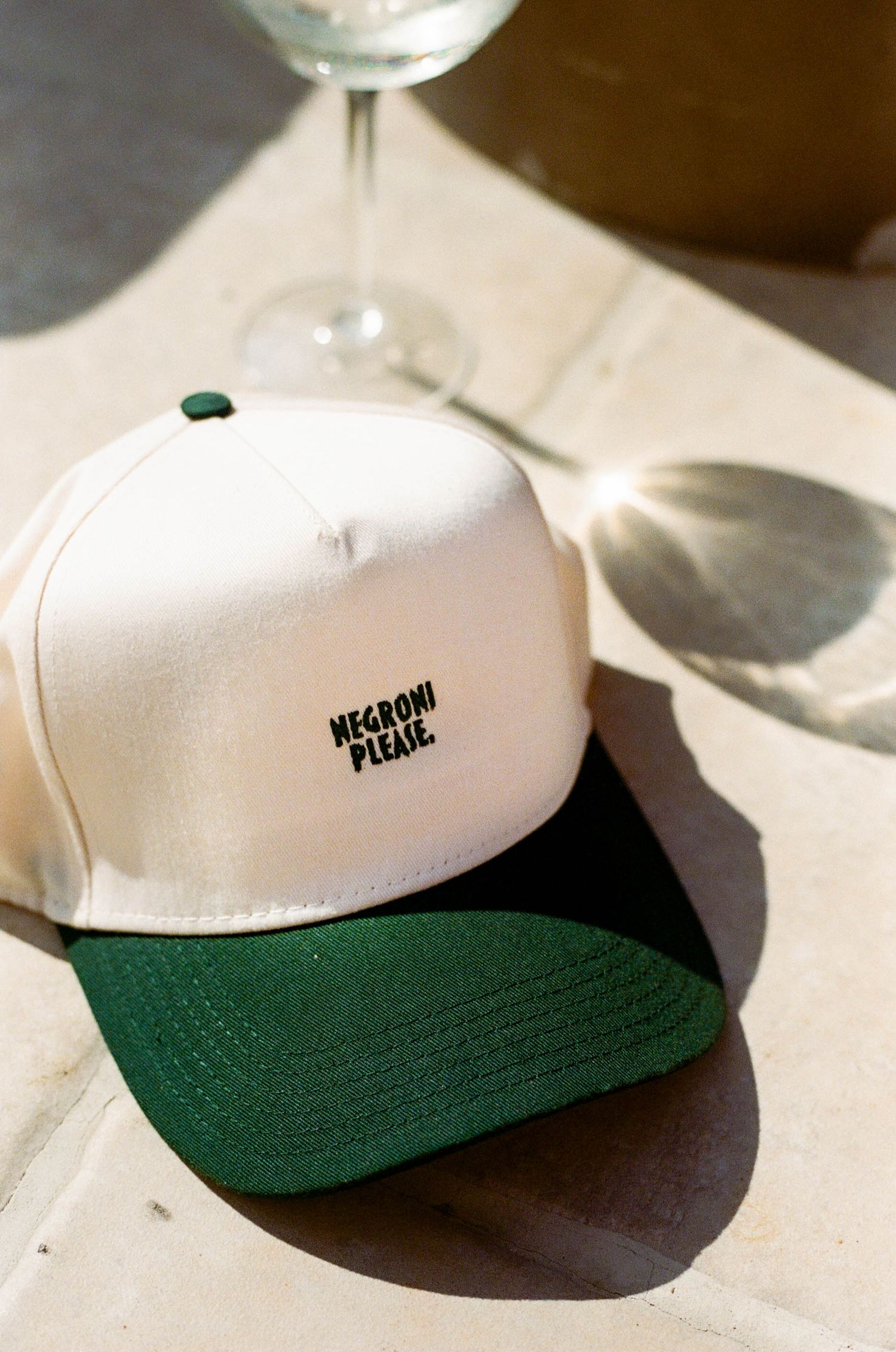 White and green baseball cap with embroidered text photographed in natural light.