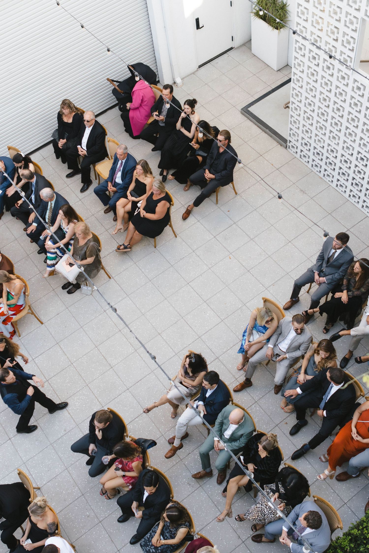Aerial view of wedding guests seated in rows on an outdoor patio.