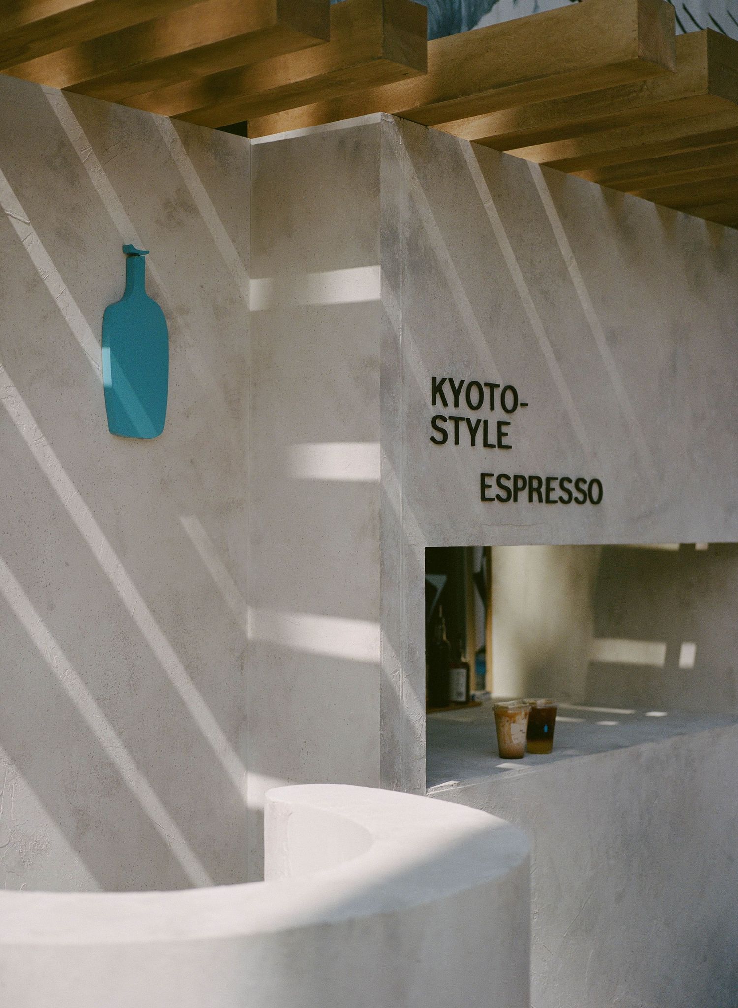 Blue Bottle Coffee Kyoto-Style Espresso bar with white marble walls and wooden ceiling casting geometric shadows.