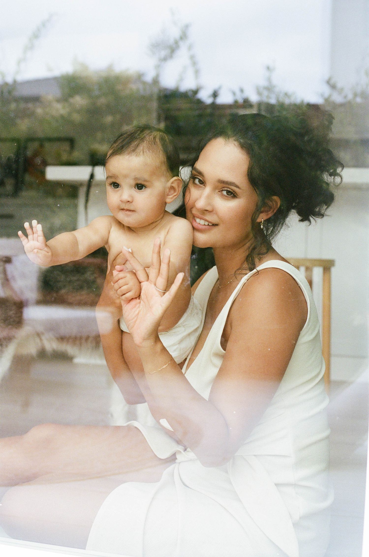 A series of four soft, dreamy photographs showing tender moments between a parent and baby in white clothing.