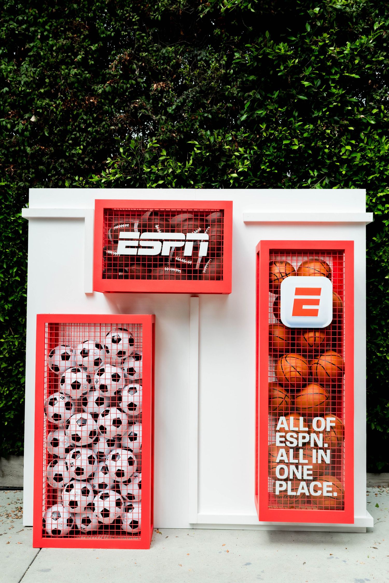White display boxes with ESPN branding and soccer ball decorations against green hedge.