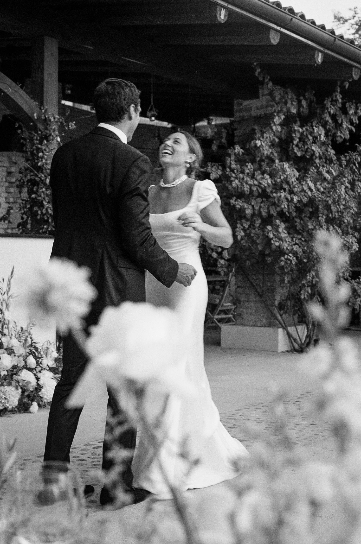 Dancing couple in black and white captured through soft focus floral elements.