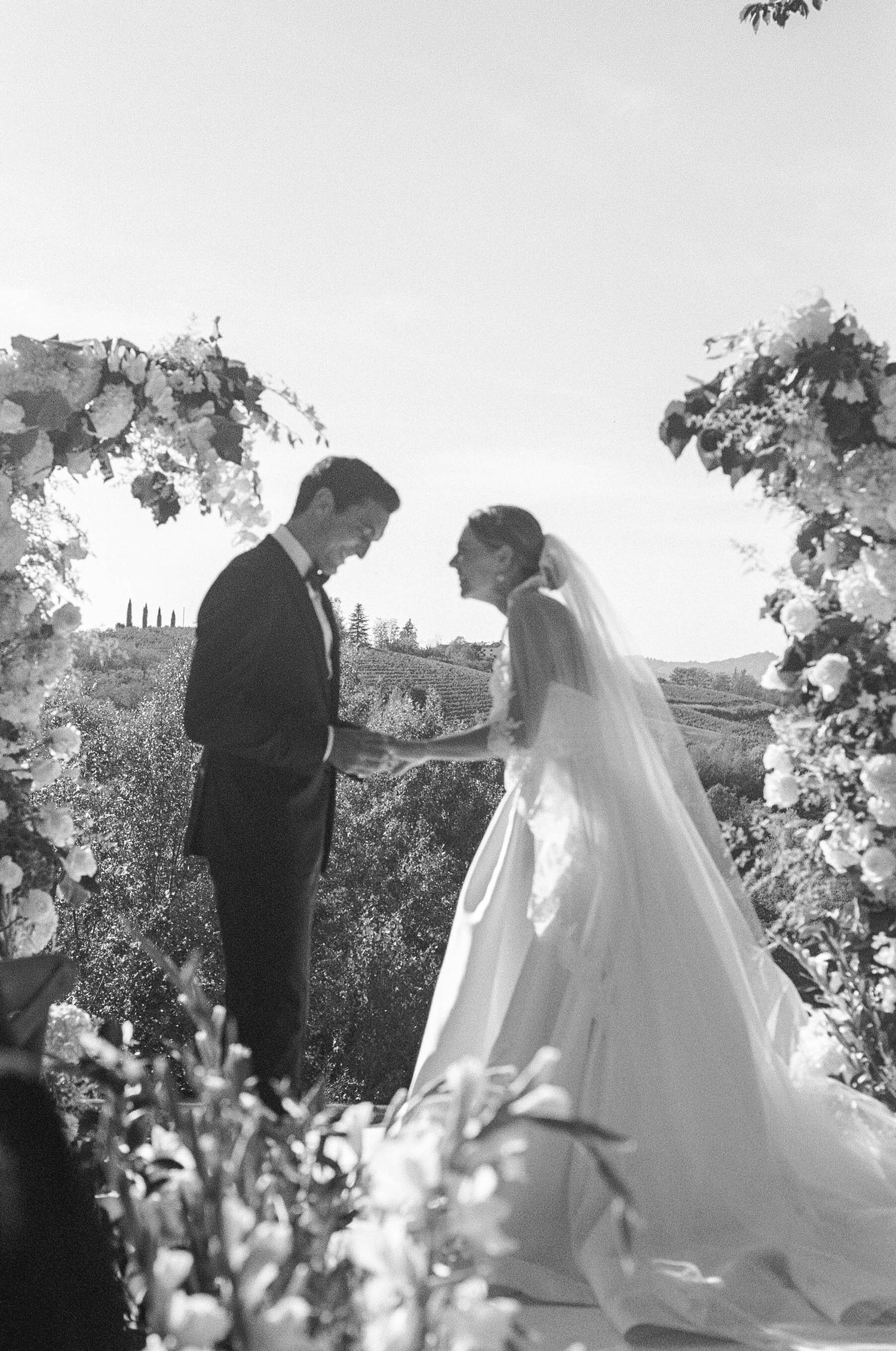 A wedding ceremony takes place in a scenic outdoor garden setting.
