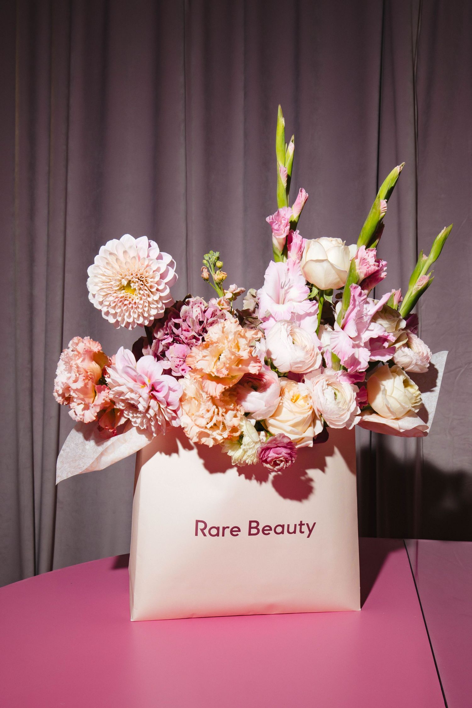 Pink and peach flowers arranged in a white box labeled 'Rare Beauty'.